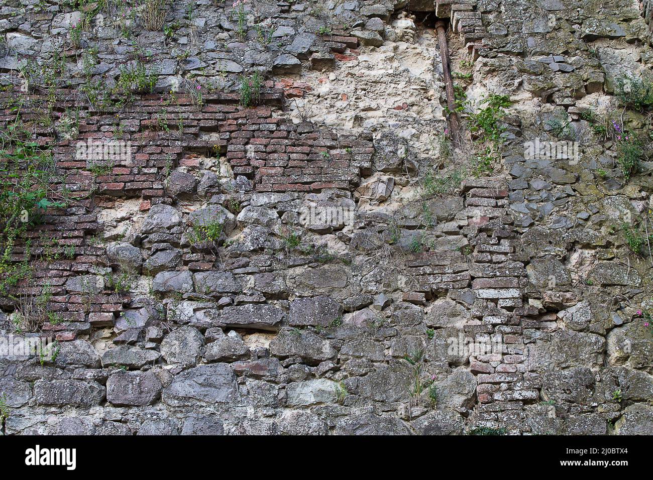 Hintergrund alte verfallene Steinmauer mit Gras überwuchert Stockfoto