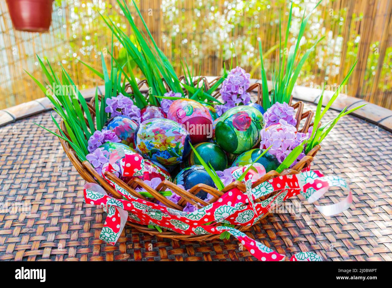 Wunderschön dekorierter Holzkorb am sonnigen Ostertag Stockfoto