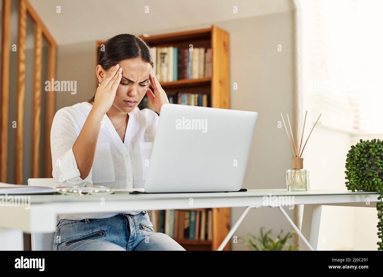 Dies war der schlimmste Tag aller Zeiten. Aufnahme einer jungen Geschäftsfrau, die bei der Arbeit von zu Hause aus Kopfschmerzen hat. Stockfoto