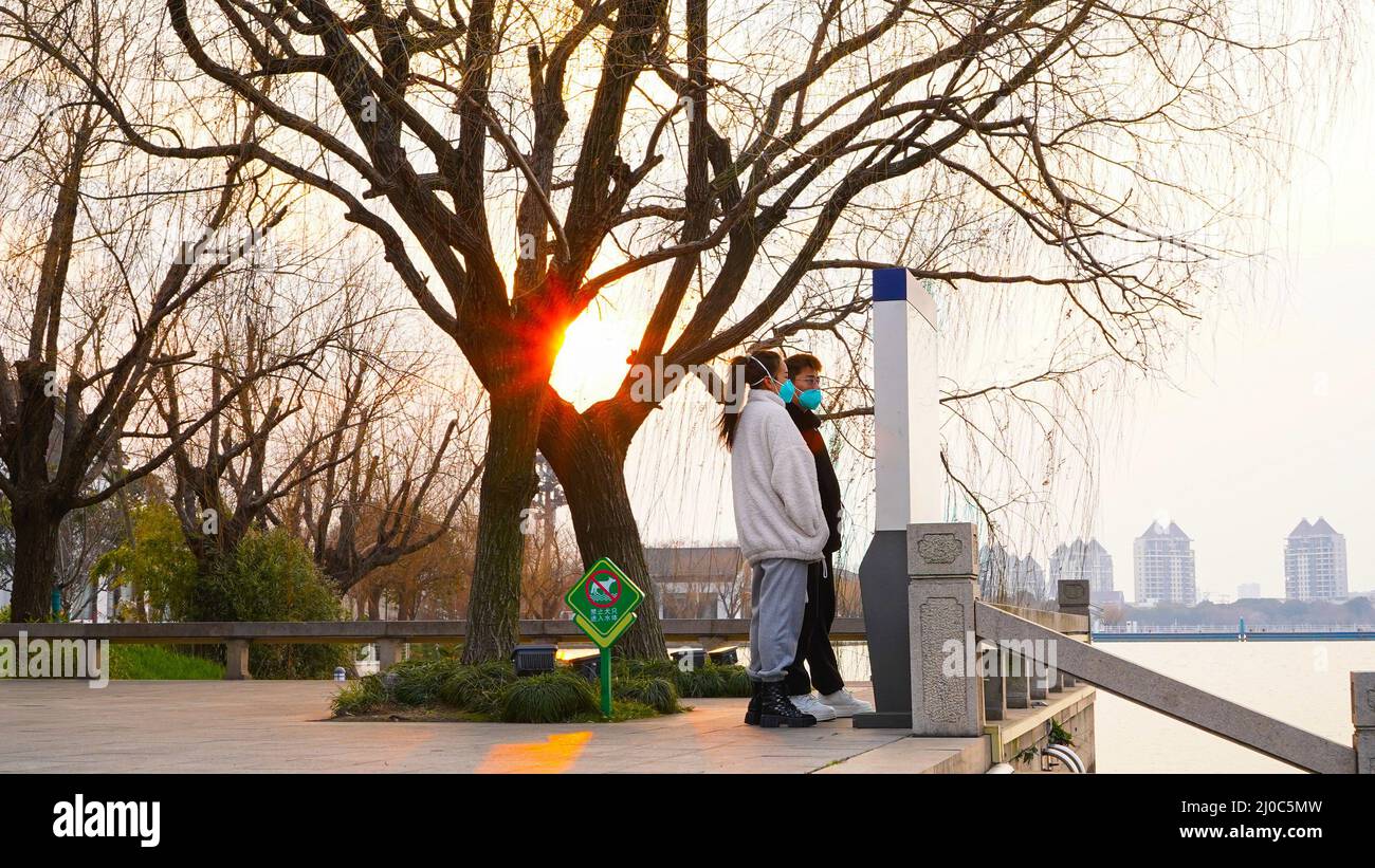 Suzhou, China. 23.. Februar 2022. Ein Paar mit Gesichtsmasken gesehen Blick auf eine Karte in einem Park mit Sonnenuntergang im Hintergrund. Suzhou ist eine Stadt, die 100 km von Shanghai entfernt liegt. Die Stadt befindet sich seit Ende Februar in Quarantäne, nachdem neue Fälle von Covid 19 entdeckt wurden. (Foto von Thibaud Mougin/SOPA Images/Sipa USA) Quelle: SIPA USA/Alamy Live News Stockfoto