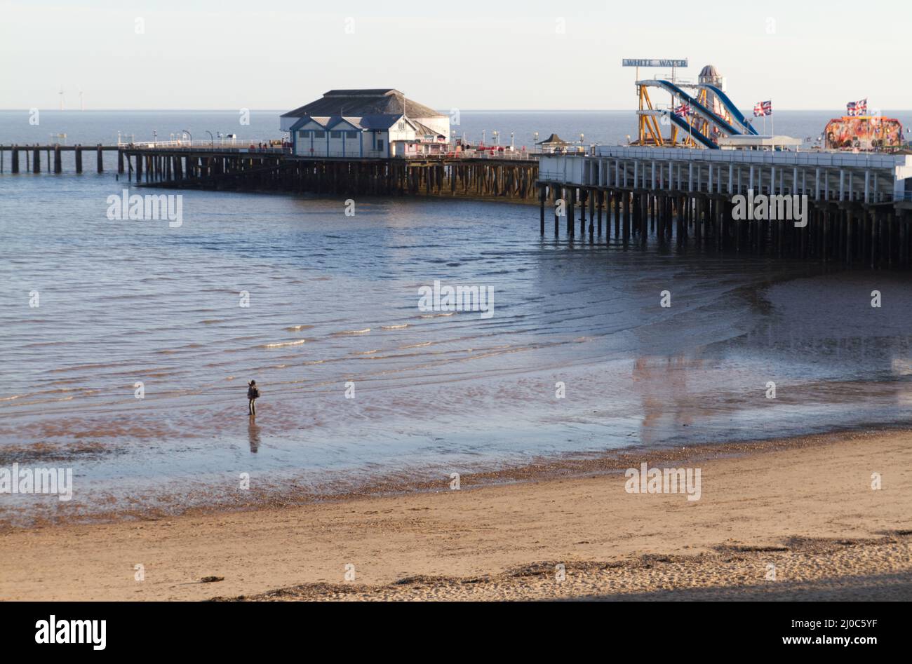 Strand bei Clacton-on-Sea, Essex, mit Blick auf den letzten Teil des Piers. Jemand hält an, um ein Foto zu machen Stockfoto