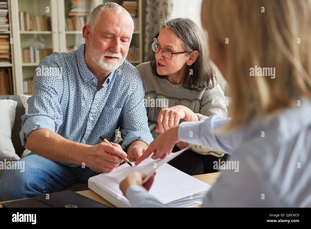 Senioren unterzeichnen nach einer Konsultation zu Hause einen Vertrag oder eine Vollmacht Stockfoto