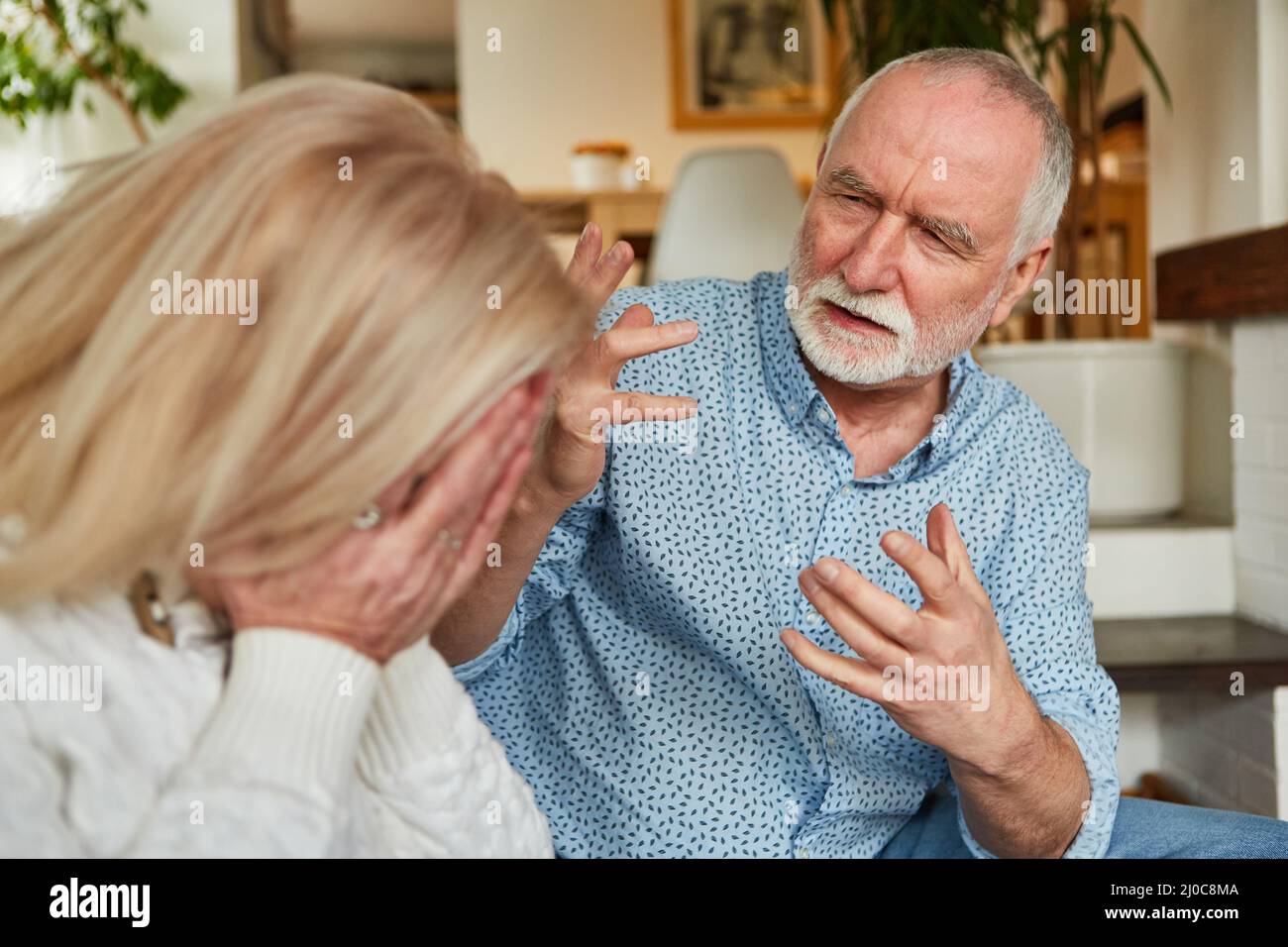 Der alte Mann streitete zu Hause mit seiner weinenden Frau als Zeichen von Konflikt und Eifersucht Stockfoto