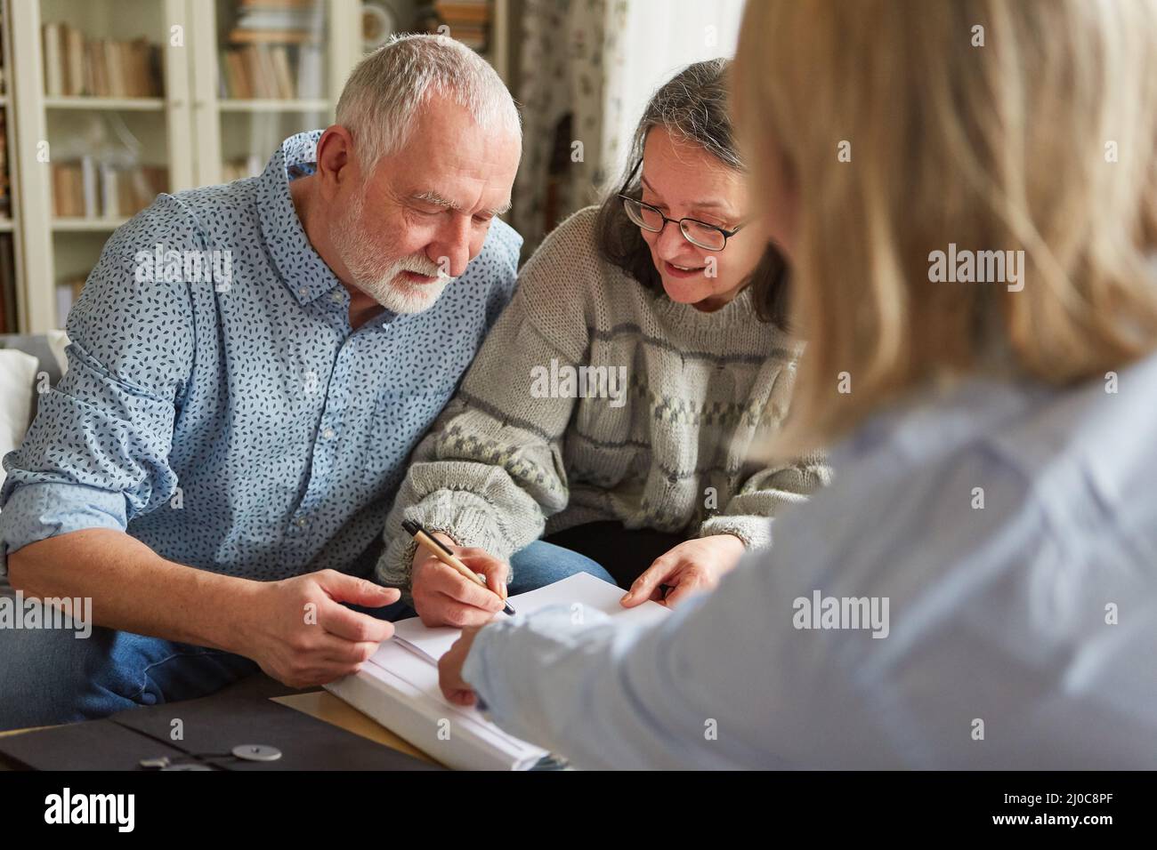 Seniorenpaar unterzeichnet einen Vertrag oder eine Vollmacht oder füllt einen Antrag aus Stockfoto
