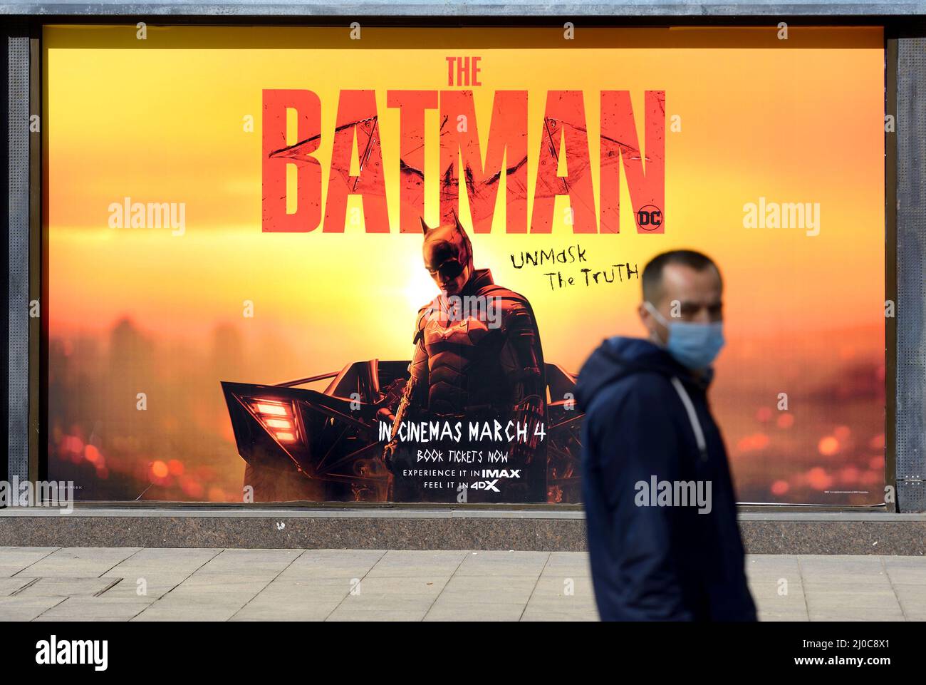 London, England, Großbritannien. Leicester Square: Poster für Batman: Unmaskierung der Wahrheit - und COVID-Maske (März 2022) Stockfoto