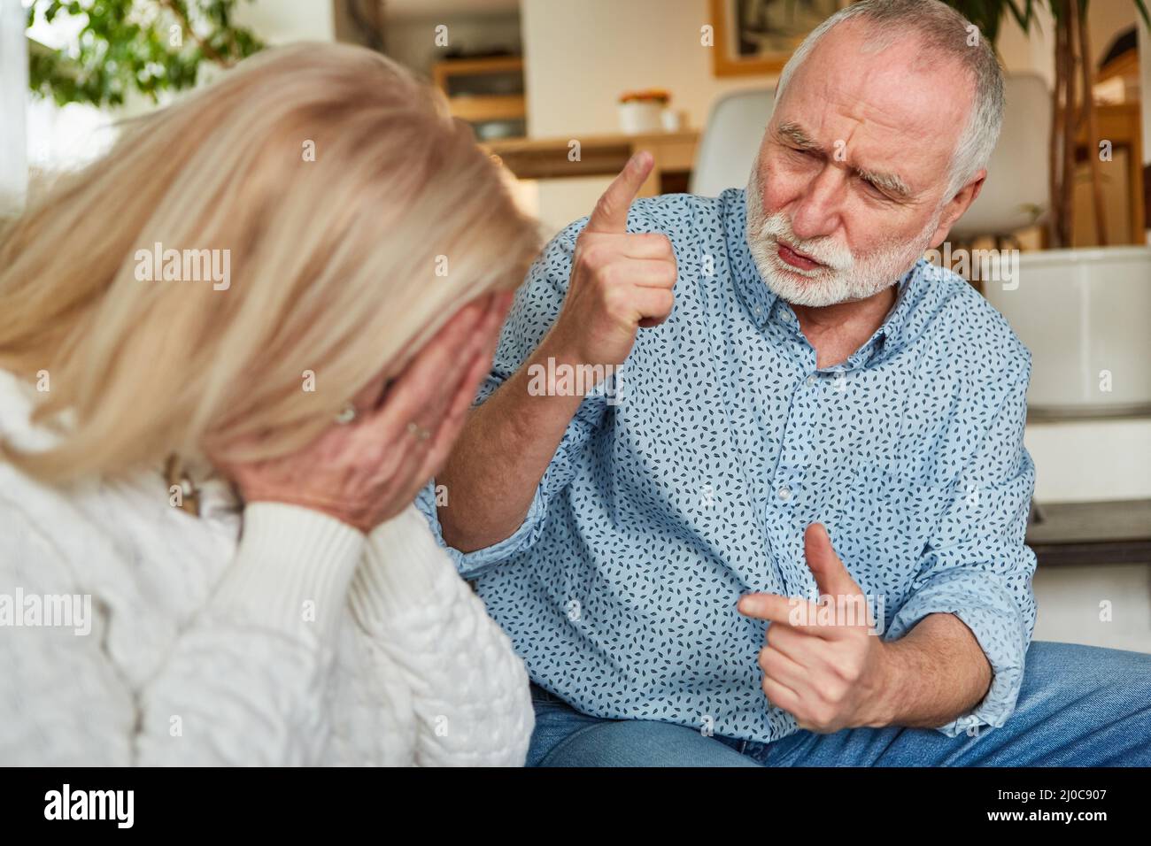 Ein älterer Mann schimpft seine weinende Frau als Zeichen von Eifersucht und Frustration Stockfoto