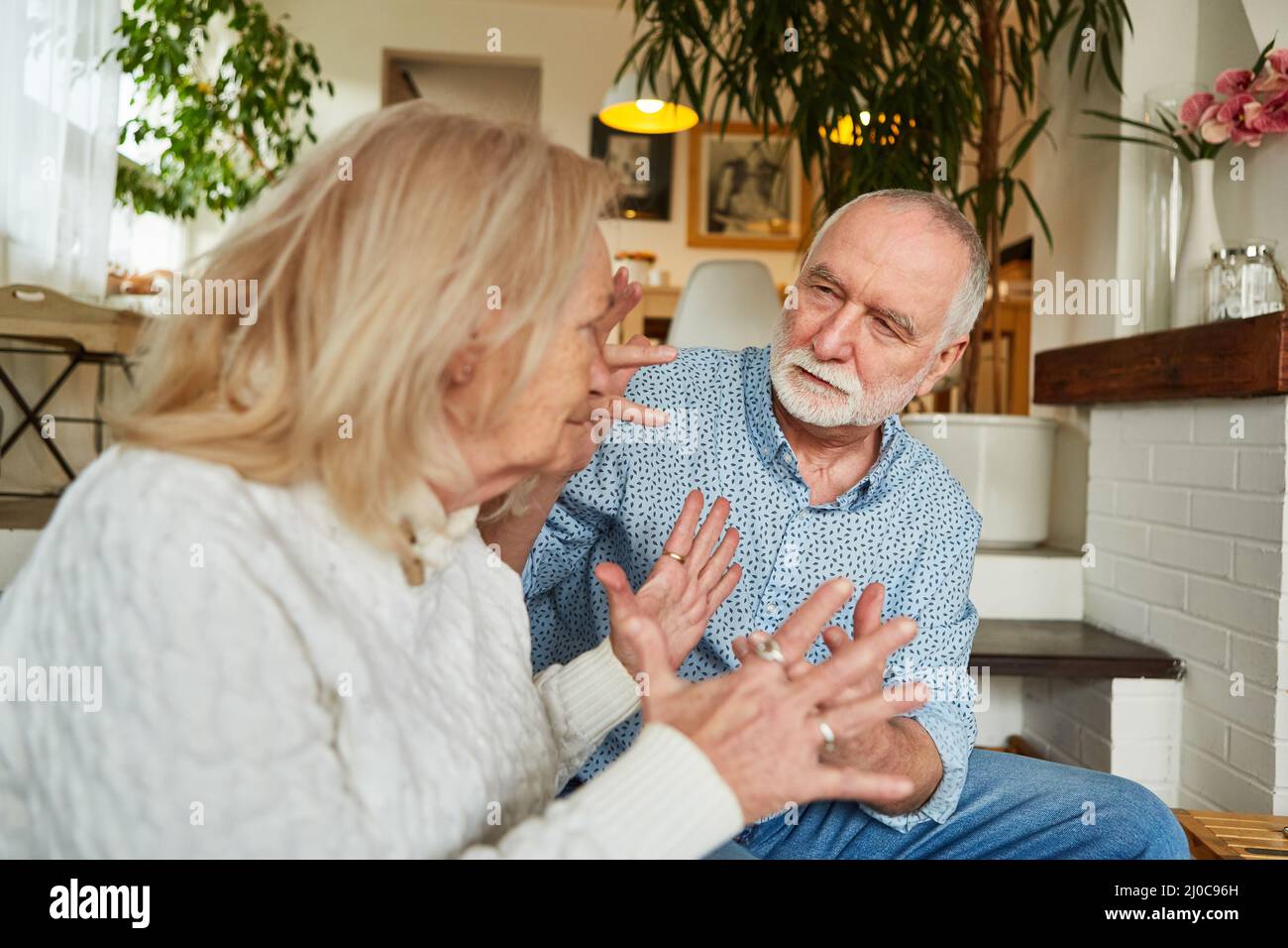 Das ältere Paar streite zu Hause im Wohnzimmer als Zeichen von Eifersucht und Beziehungskonflikten Stockfoto