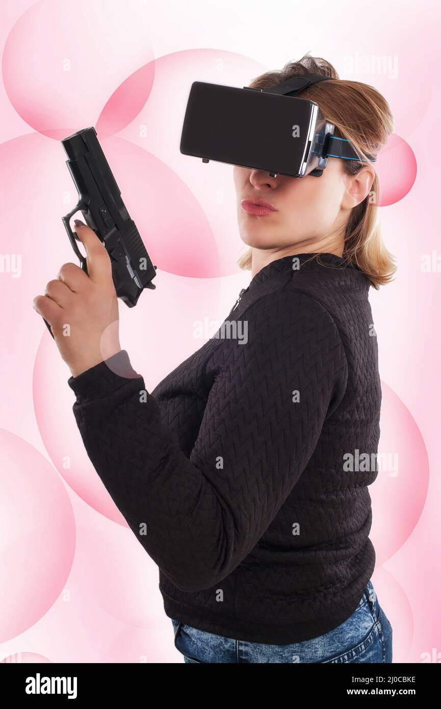 Frau spielen VR-Shooter-Spiel mit Virtual-Reality-Pistole und VR-Brille. Studioaufnahmen. Stockfoto