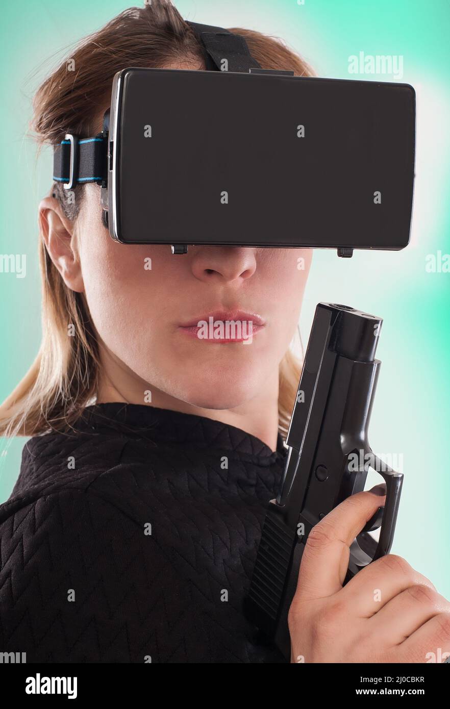 Frau spielen VR-Shooter-Spiel mit Virtual-Reality-Pistole und VR-Brille. Studioaufnahmen. Stockfoto