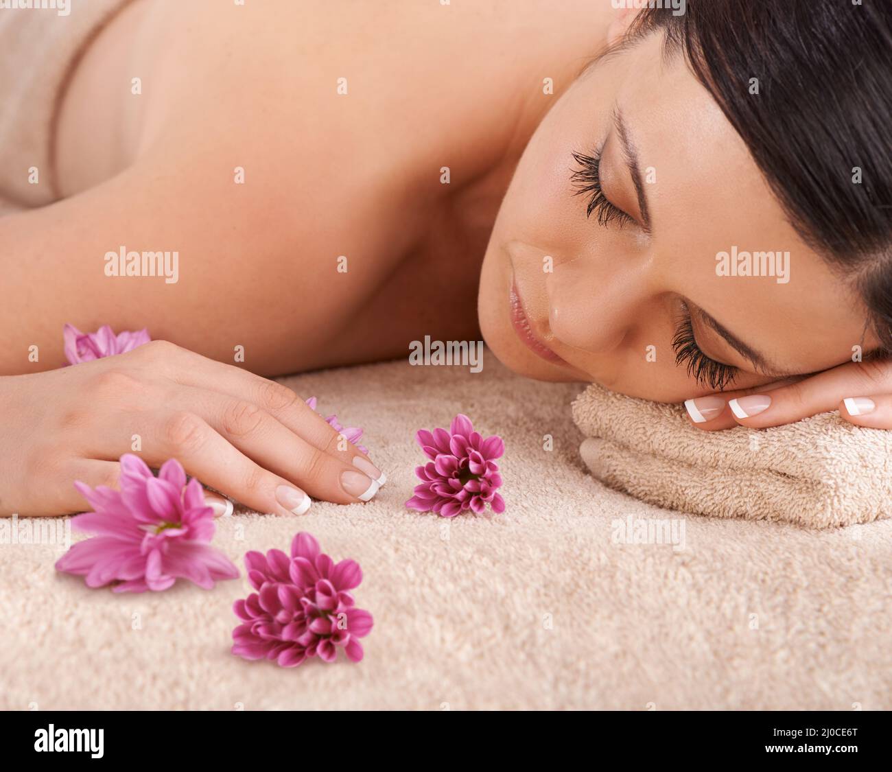 Natürliche Schönheit beginnt mit einer Auszeit. Kurzer Blick auf eine junge Frau, die sich in einem Spa mit einer frischen Blume in der Nähe entspannt. Stockfoto