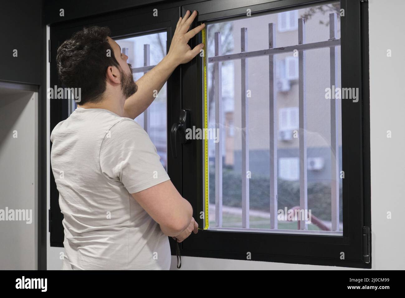 Mann, der Fensterglas misst, um mattiertes Fenstervinyl zu installieren. Stockfoto