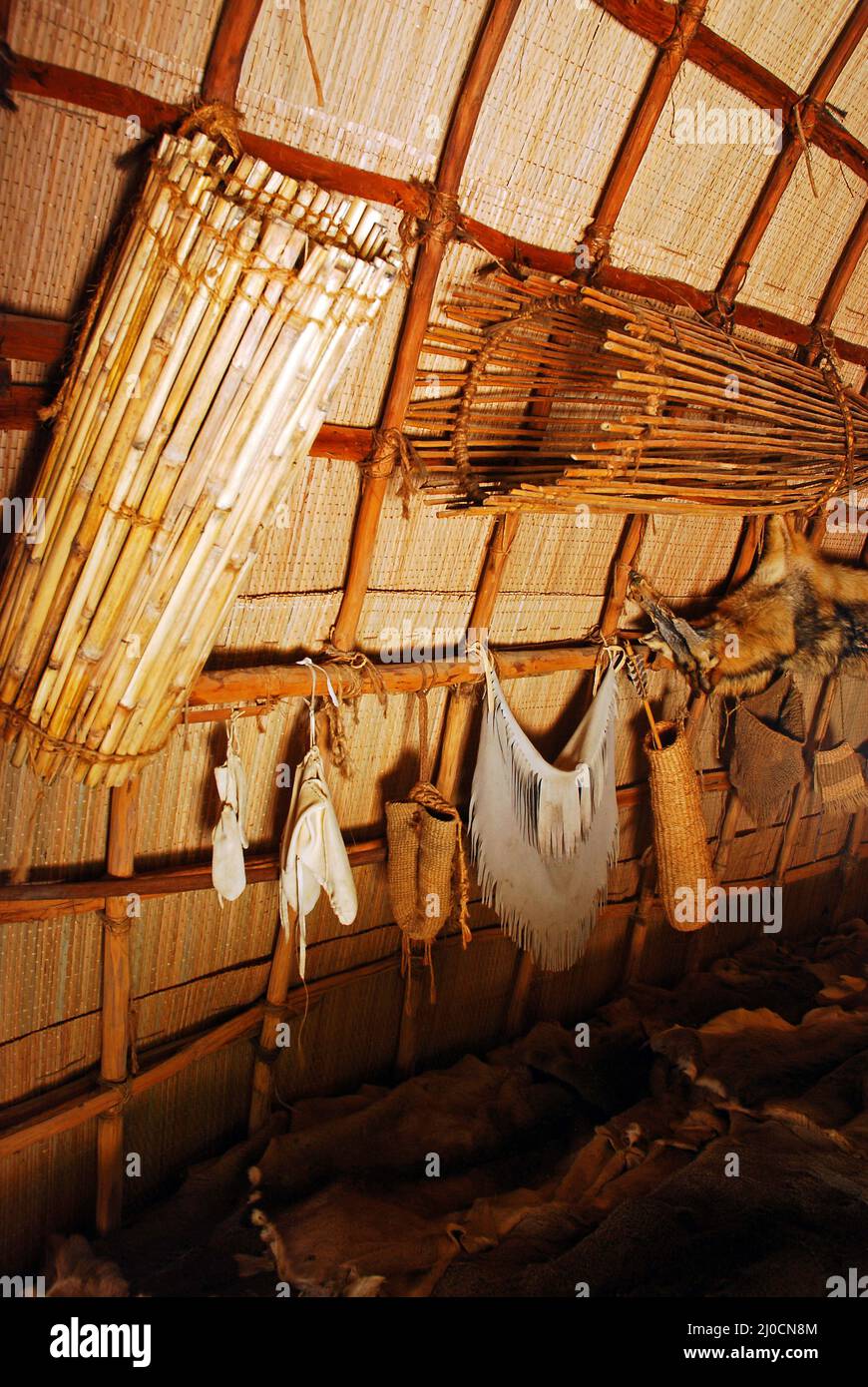 Tierhäute und Fischkörbe hängen an einem neu erfundenen Powhatan Longhouse Stockfoto