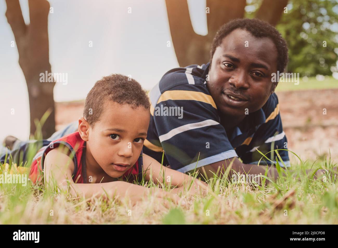 Vater und Sohn haben Spaß und liegen auf dem Gras und genießen im Park Stockfoto