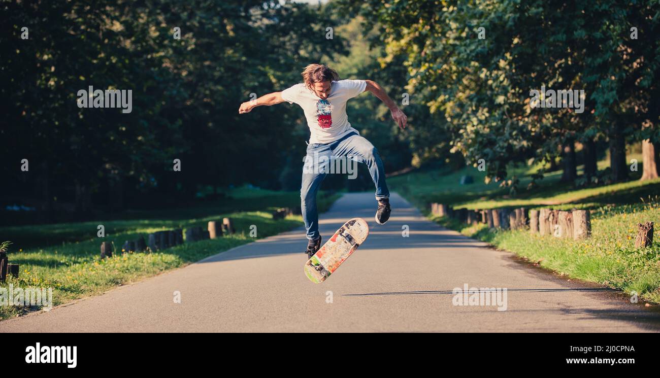 Action-Aufnahme eines Skateboarders beim Skaten, beim Kunststück und beim Springen auf der Straße durch den Wald. Freies Reiten Skateboard Stockfoto