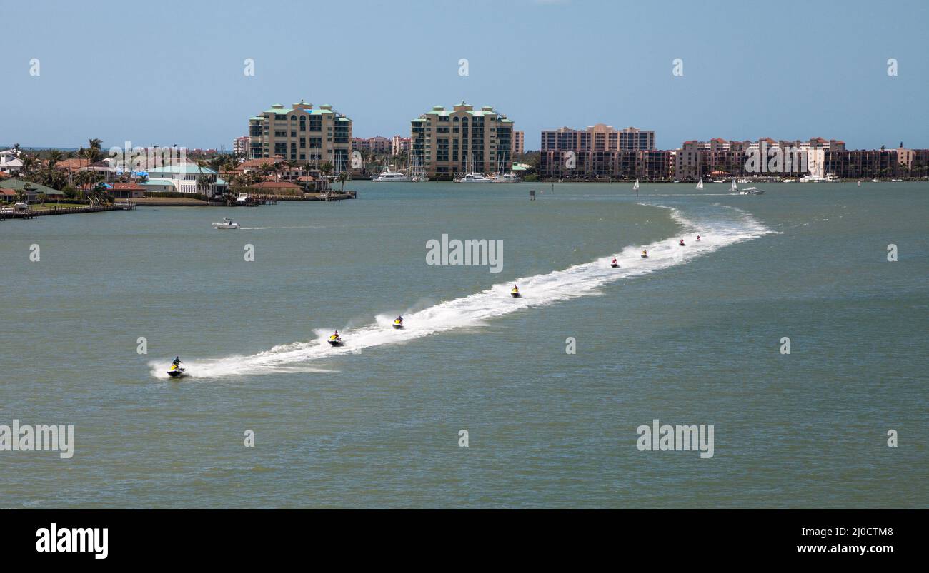 Skyline im Hintergrund, als eine Gruppe von Jet Skies zip am Ozean entlang Stockfoto