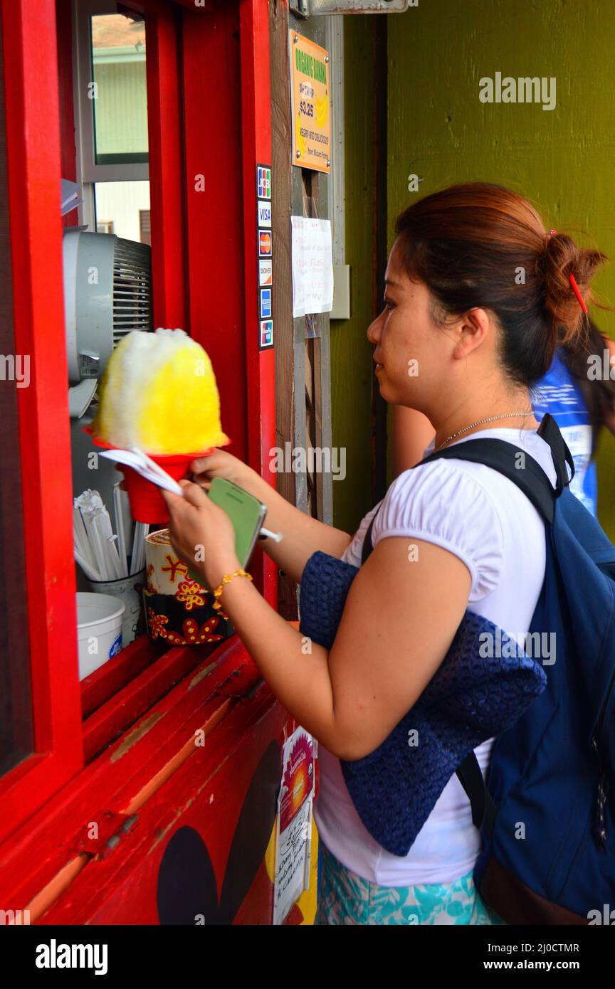 Eine junge Frau bereitet sich darauf vor, ihr großes Rasiereis zu genießen, das sie von einem Imbissstand in Kauai Hawaii gekauft hat Stockfoto