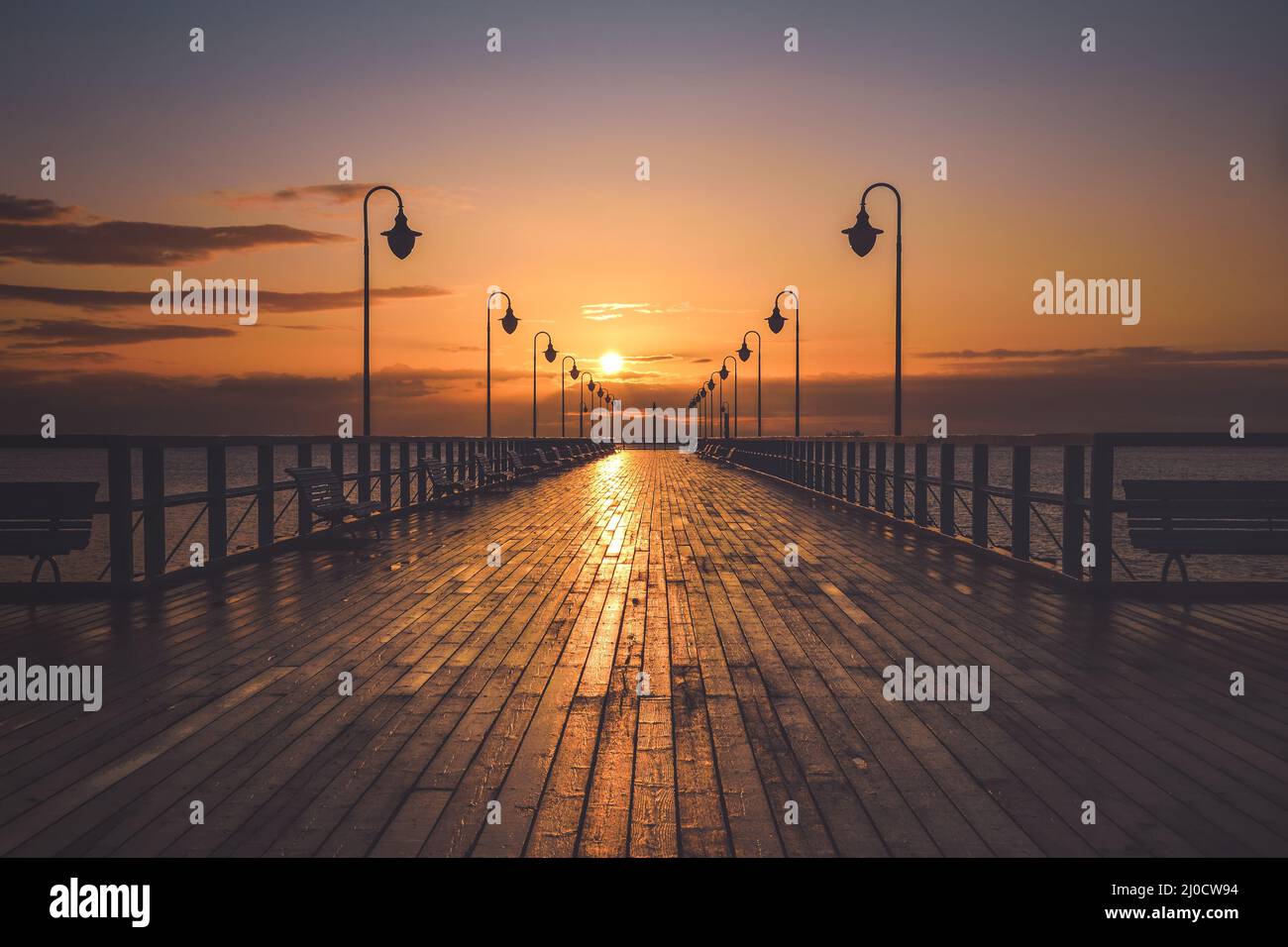 Wunderschöne Landschaft am Morgen am Meer. Hölzerner Pier mit einem bunten Himmel in Gdynia Orlowo, Polen. Stockfoto