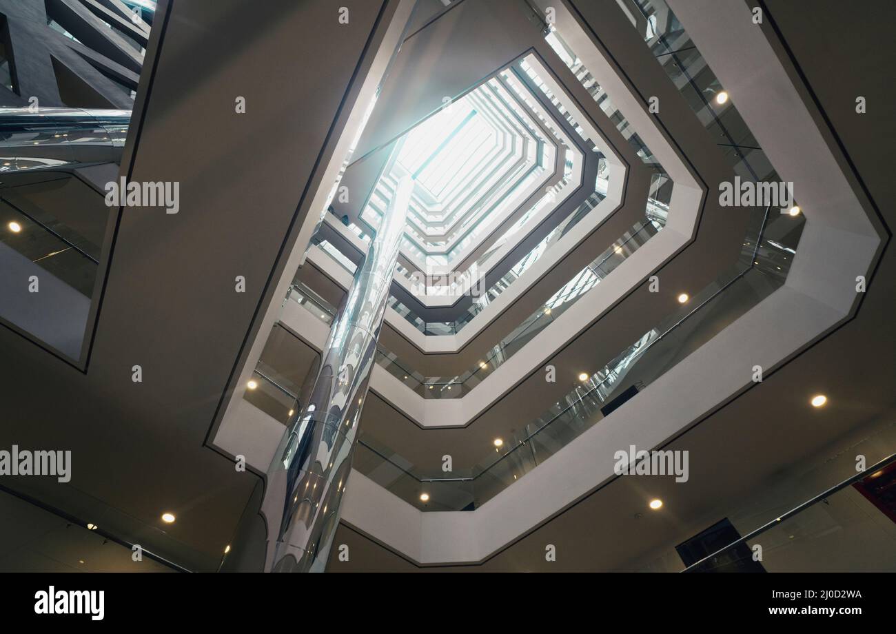 Blick von unten auf die innere Metall- und Glasstruktur eines leeren modernen Gebäudes ohne Menschen mit Licht von oben Stockfoto