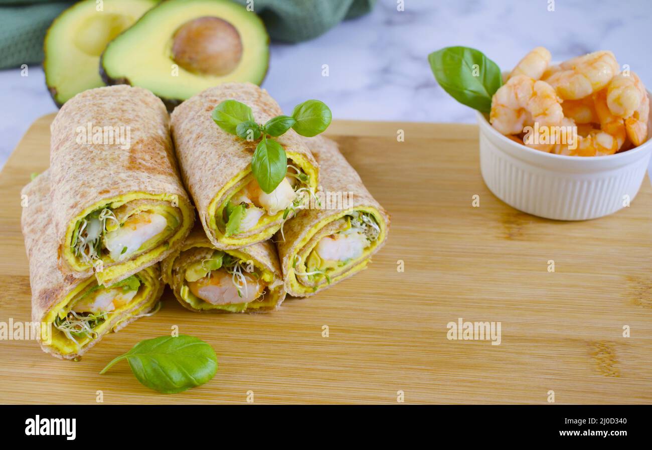 Käsetortilla mit Avocado-Garnelen und Gemüse auf Holzschneidebrett. Tortilla mit Gemüse, Garnelen und Luzerne gekeimt. Tortilla aus Stockfoto