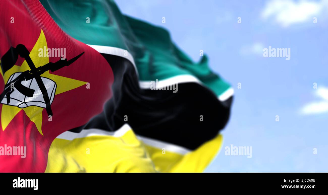 Detail der Nationalflagge von Mosambik, die an einem klaren Tag im Wind winkt. Mosambik ist ein Land im Südosten Afrikas. Selektiver Fokus. Stockfoto