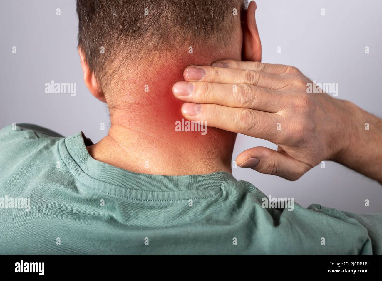 Mann, der an Nackenschmerzen leidet. Kopf zurück mit roten Punkt Nahaufnahme. Gesundheitsprobleme und Medizinkonzept. Hochwertige Fotos Stockfoto