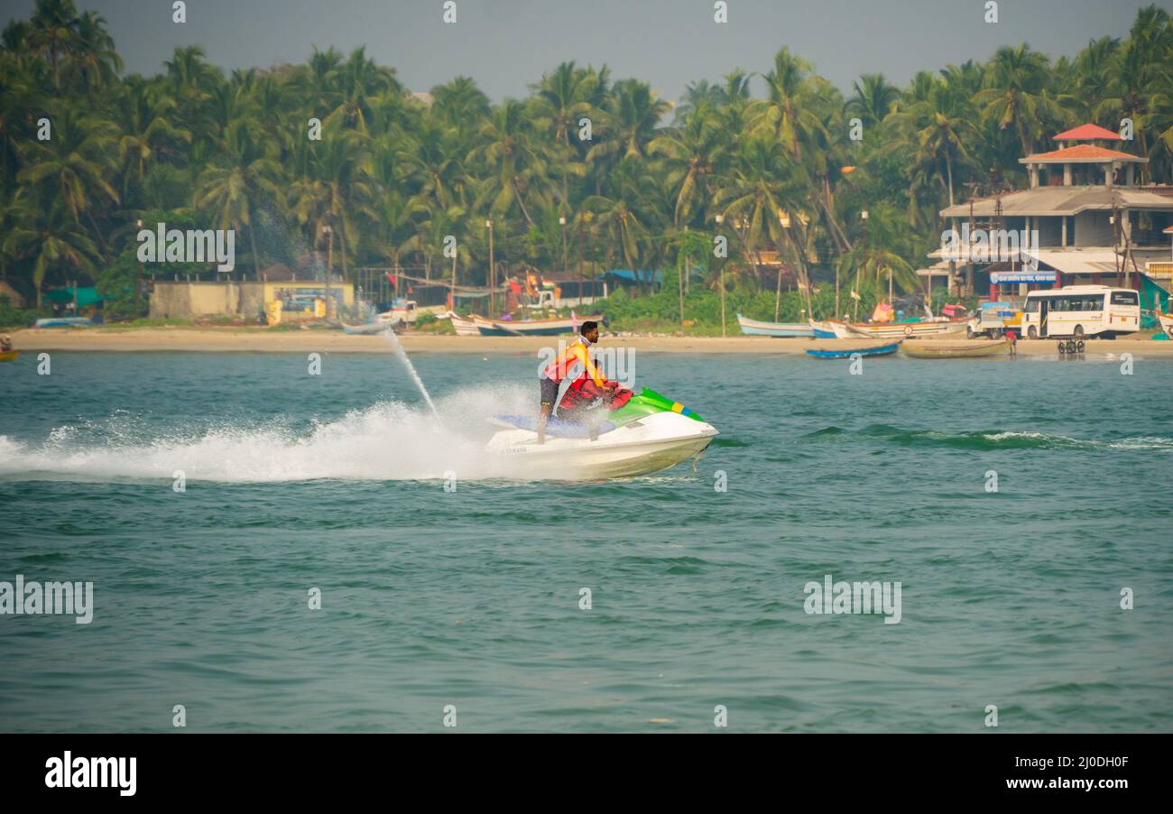 Malvan, INDIEN - 23. Dezember 2021 : nicht identifizierter Tourist, der eine Jet-Ski-Fahrt am Strand von Tarkarli genießt. Der Strand ist berühmt für verschiedene Wassersportarten Stockfoto