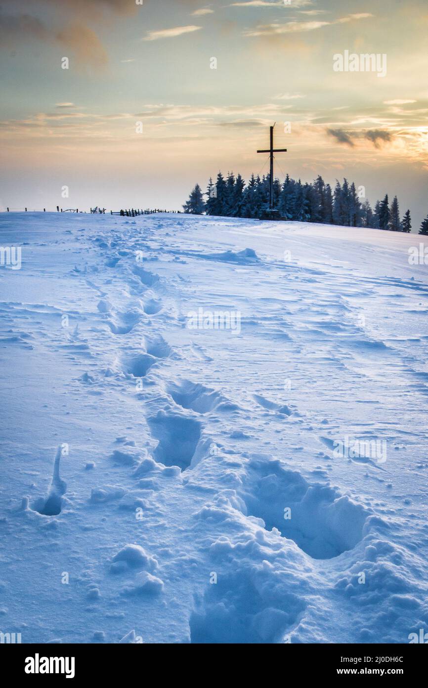 Fußtreppen im Schnee, die zum Gipfelkreuz am Schoeckl in Österreich bei Graz führen Stockfoto