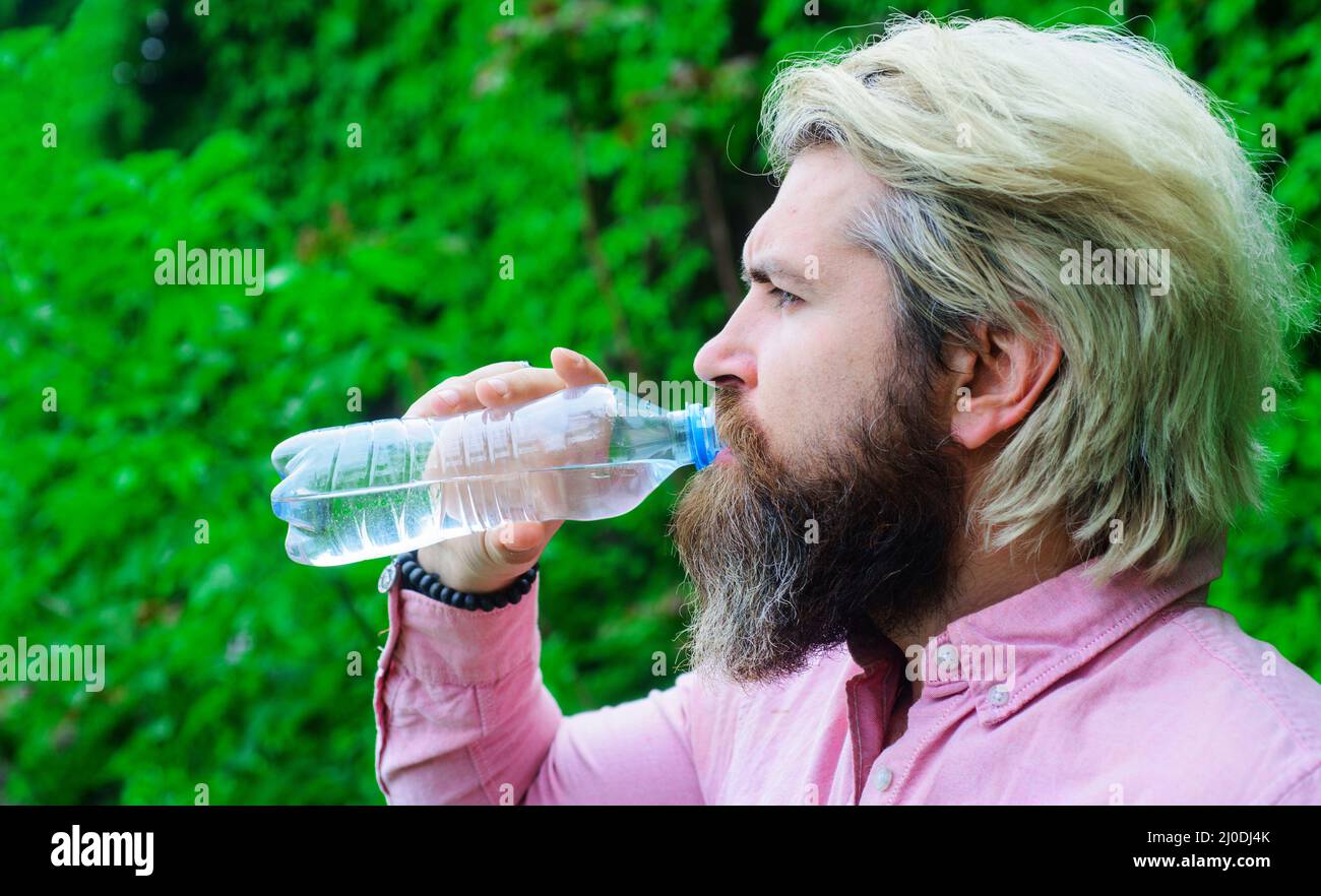 Bärtiger Mann, der im Freien Wasser aus der Flasche trinkt. Hydratationskonzept. Gesunder Lebensstil. Stockfoto