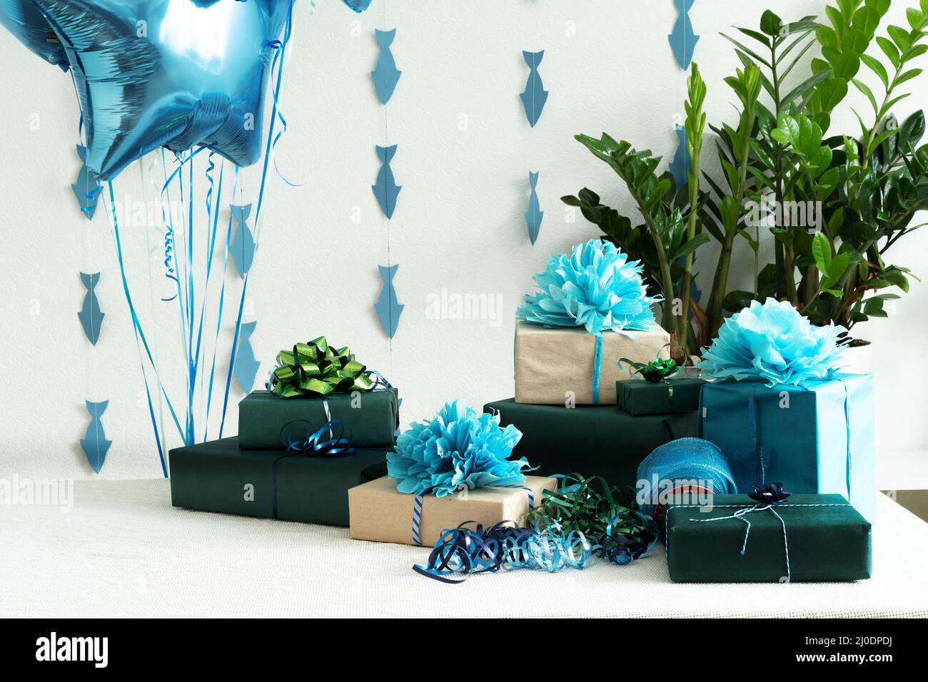 Blaue Gel-Kugeln und Geschenkboxen und Flaggen auf dem Tisch. Das Konzept eines Geburtstags, einer Hochzeit oder Weihnachten oder eines Urlaubs. Horizontales Foto. Stockfoto