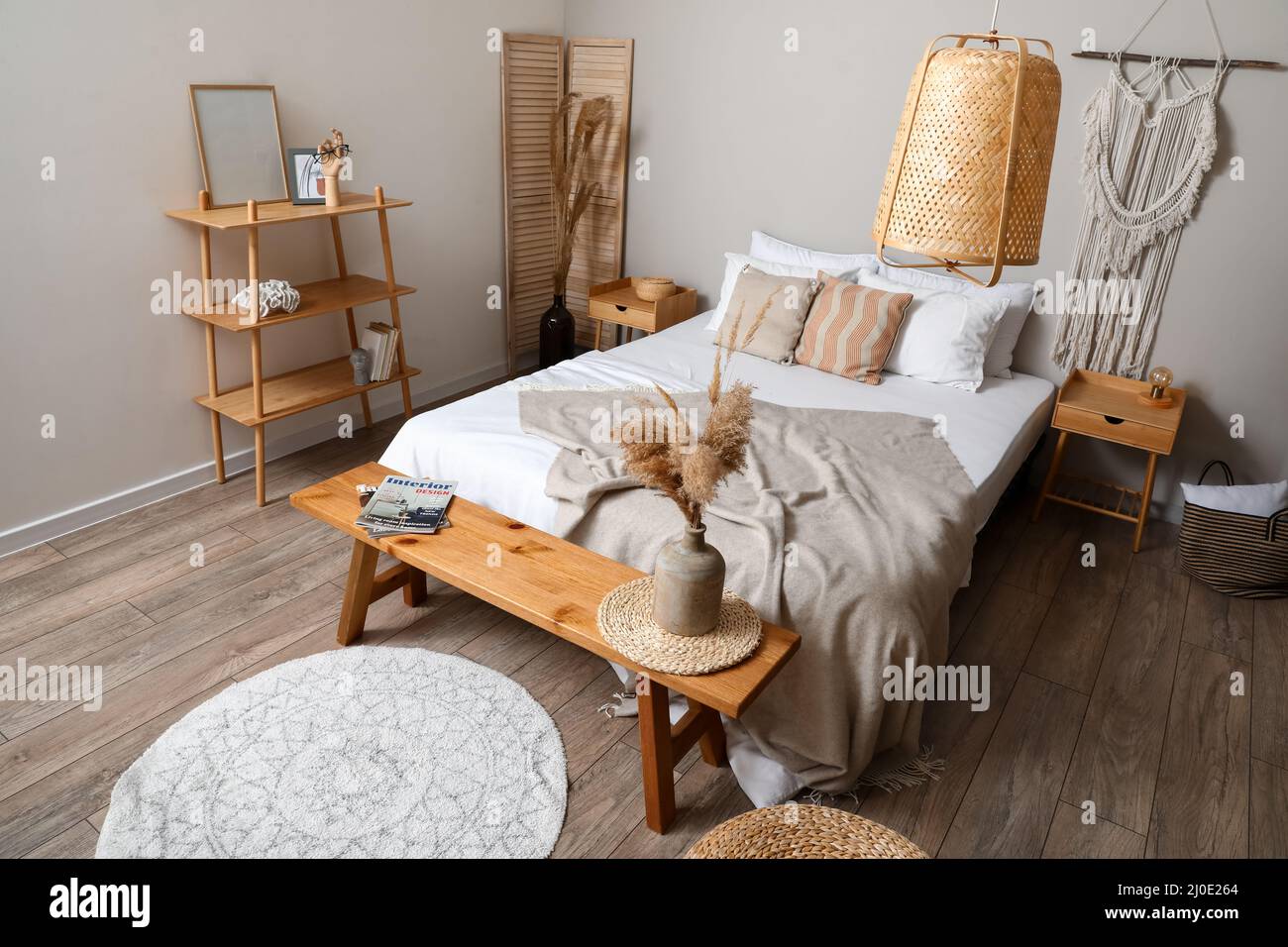 Holzbank mit Einrichtung neben dem Bett im stilvollen Schlafzimmer Stockfotografie