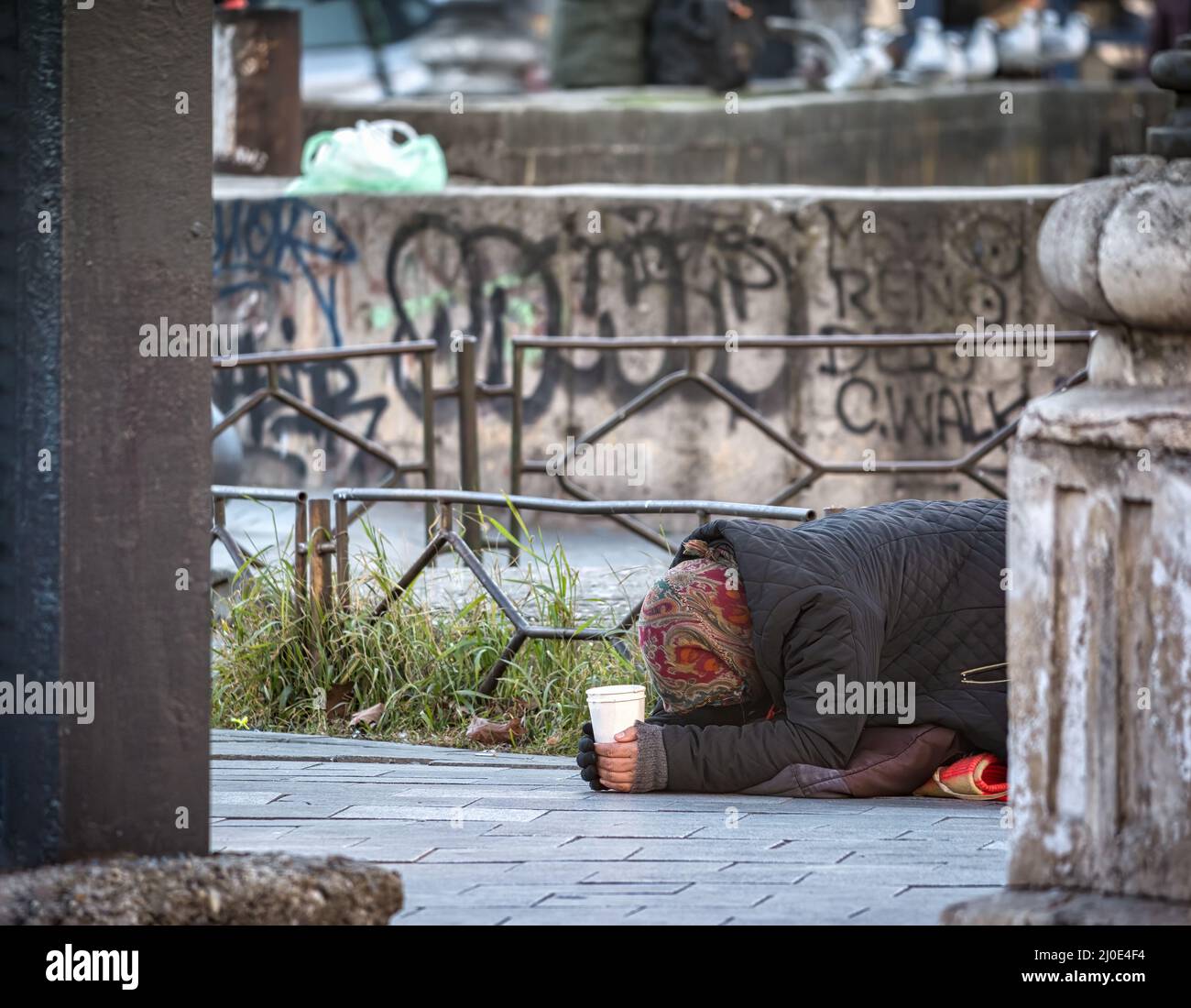 Alte ältere arme Frau mit dem Gesicht nach unten auf dem Seitenweg. Bettler im Zentrum von Bukarest, Rumänien Stockfoto