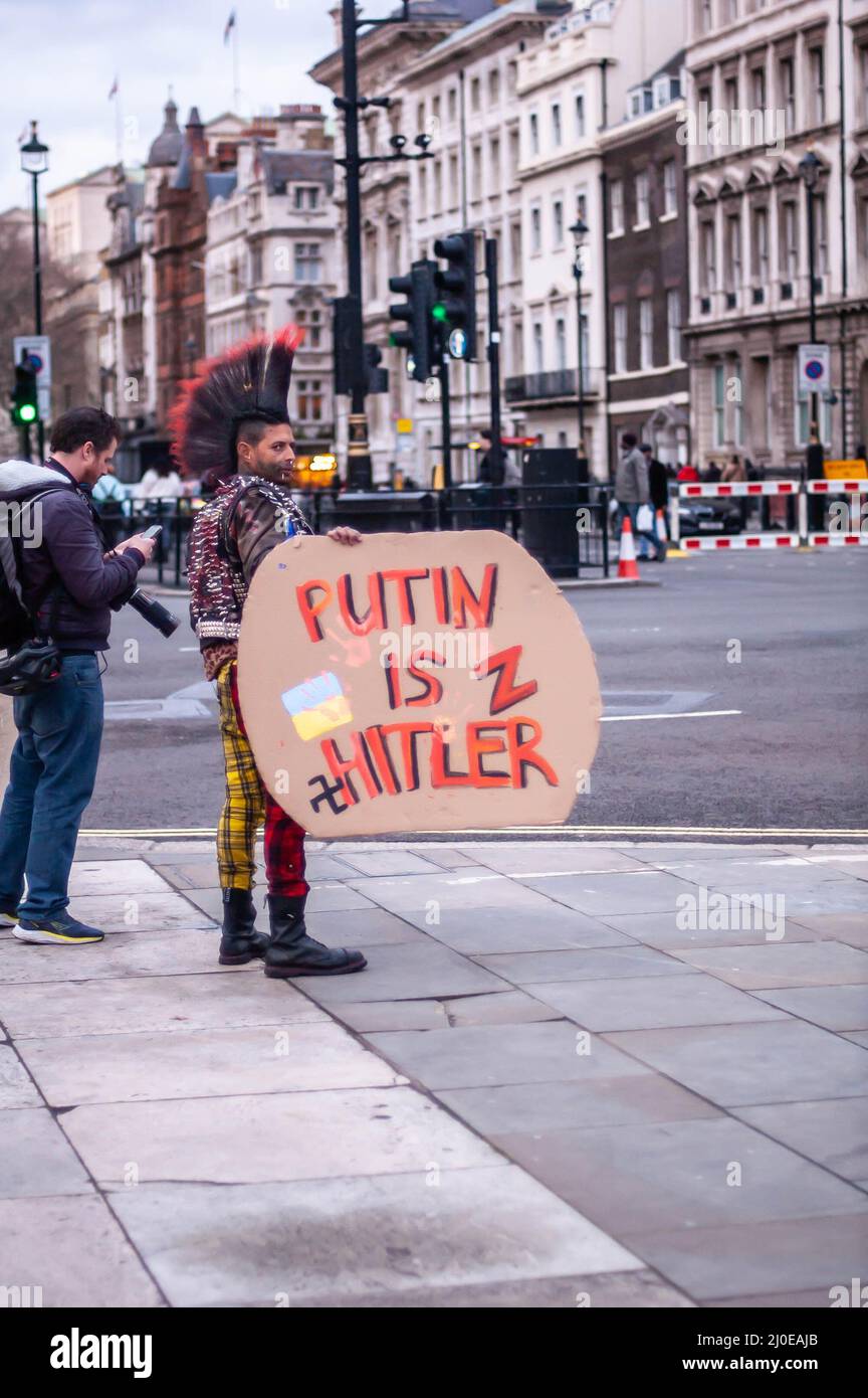 LONDON, ENGLAND - 13. März 2022: Anderson Garcia Rodrigues posiert mit PUTIN UND IST HITLERS Plakat Stockfoto