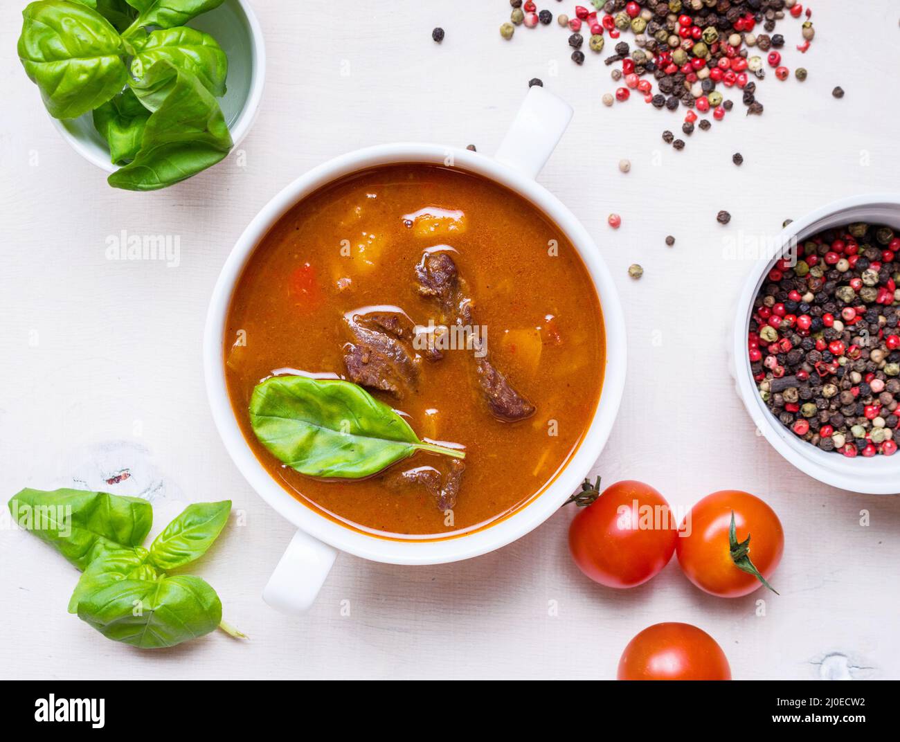 Tomatensuppe mit Fleisch in einer weißen Schüssel auf weißem Holz- Hintergrund Stockfoto