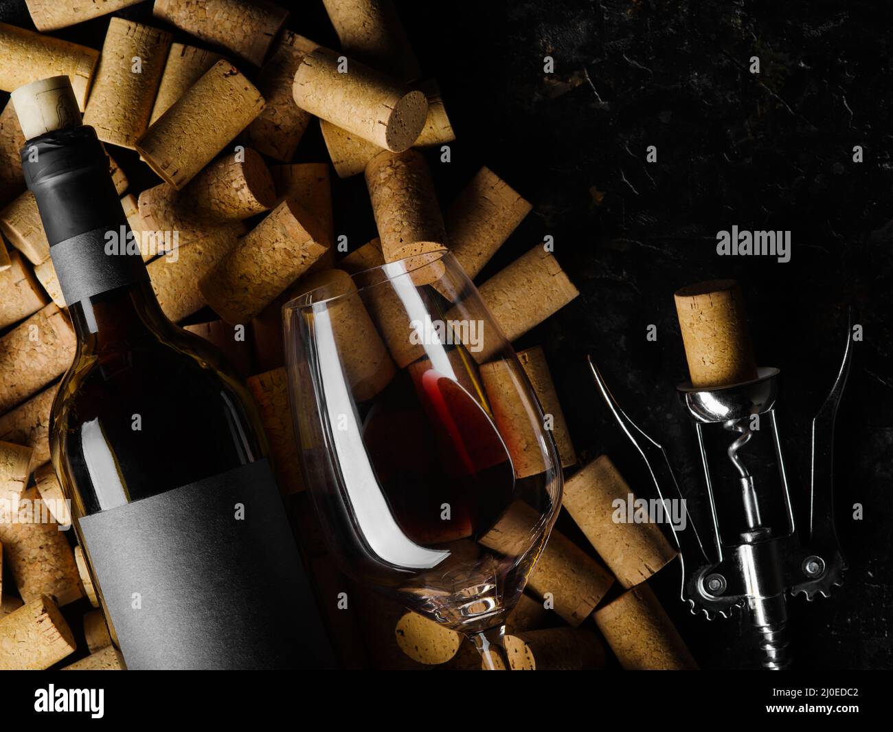 Nahaufnahme. Eine Flasche Rotwein, ein Weinglas, ein Korkenzieher und viele Weinkorken auf schwarzem Hintergrund. Weinsammlung, Weinkeller, Weinprobe, s Stockfoto