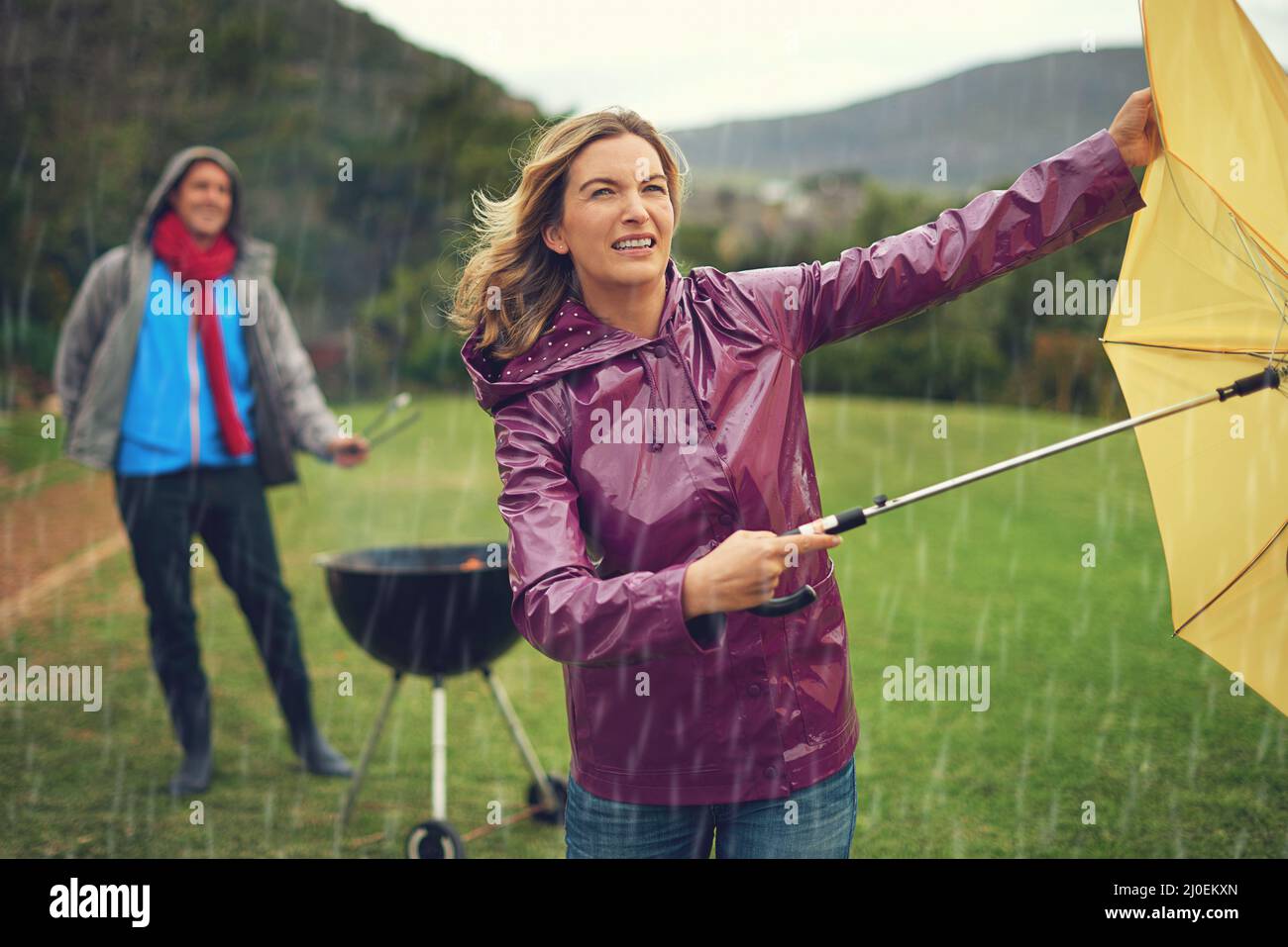 Wir werden uns nicht von einem schlechten Wetter abhalten lassen. Aufnahme eines Paares, das im Regen grillen wollte. Stockfoto