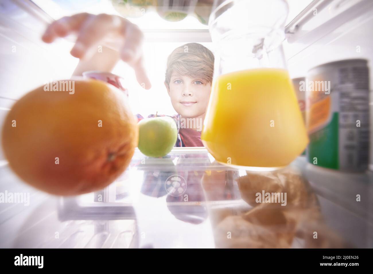 Die richtige Wahl treffen Ein kleiner Junge, der in den Kühlschrank griff, um einen Snack zu essen. Stockfoto