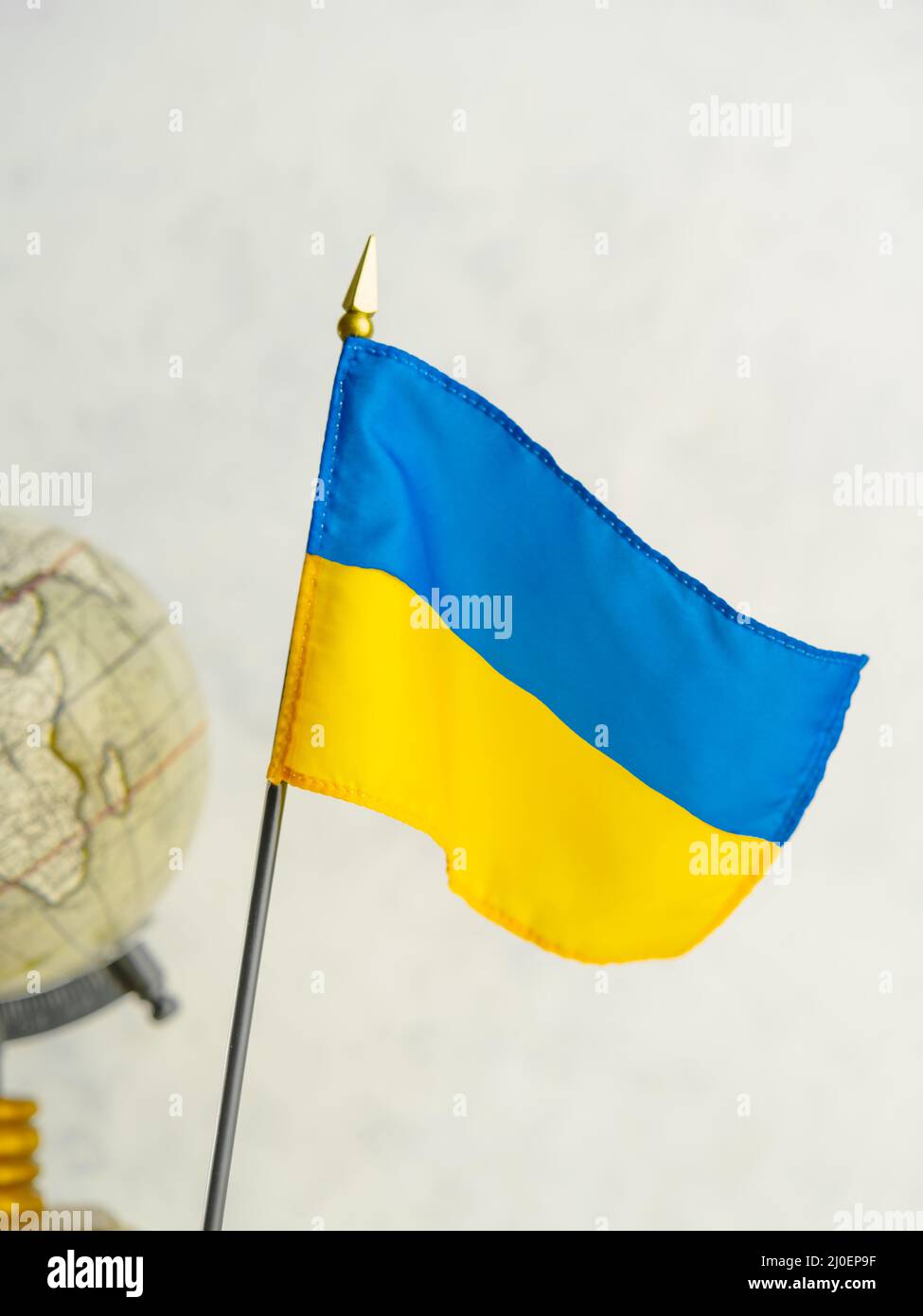 Globus der Welt und die Flagge der Ukraine. Der Platz der Ukraine in der Weltgeopolitik. Der Weg zur Mitgliedschaft in der Europäischen Union, der Kampf Stockfoto