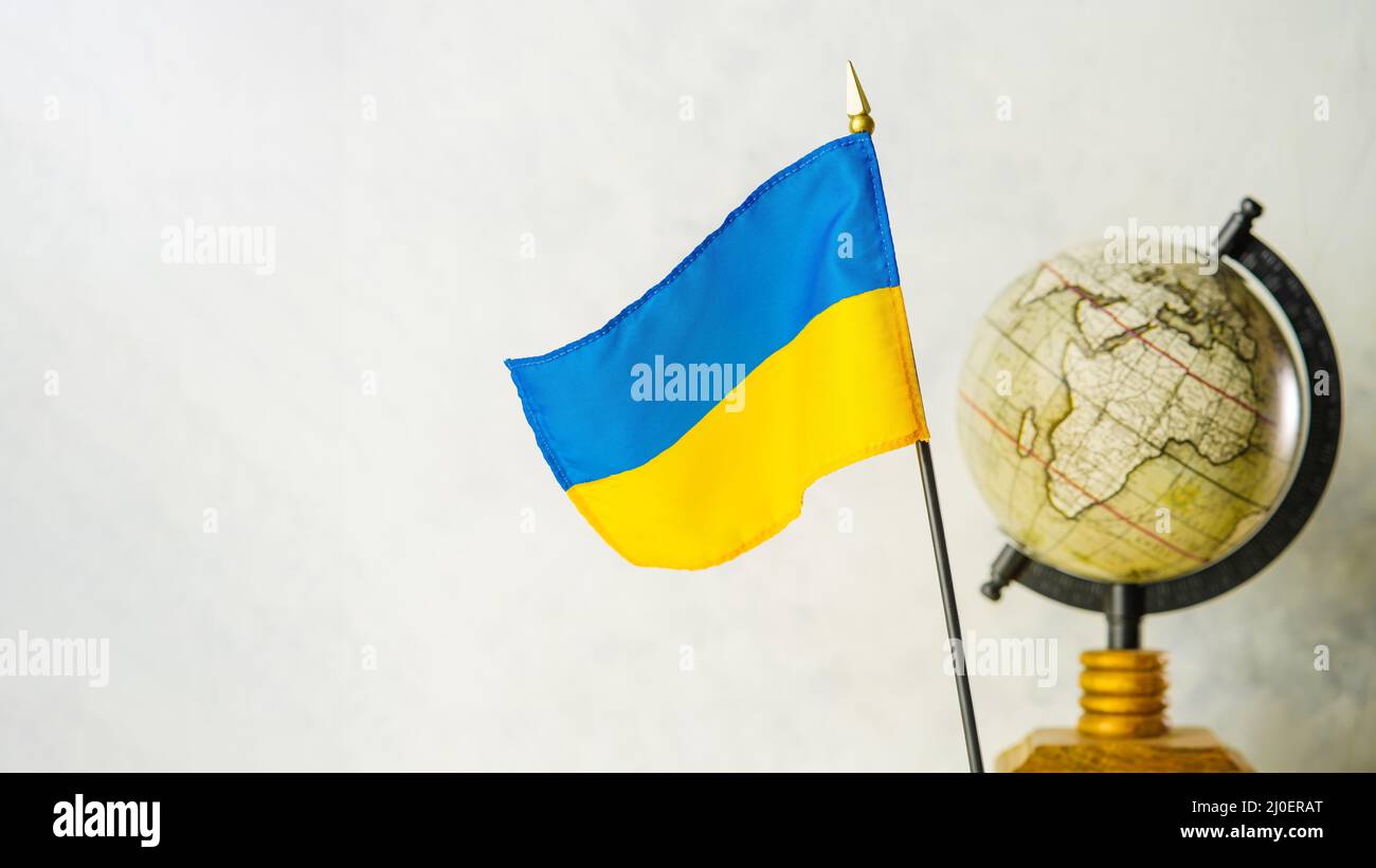 Globus und Nationalflagge der Ukraine. Die Ukraine in der Geopolitik, Russlands Invasion des Territoriums eines unabhängigen Staates, Krieg, Tötungen von Zivilisten Stockfoto