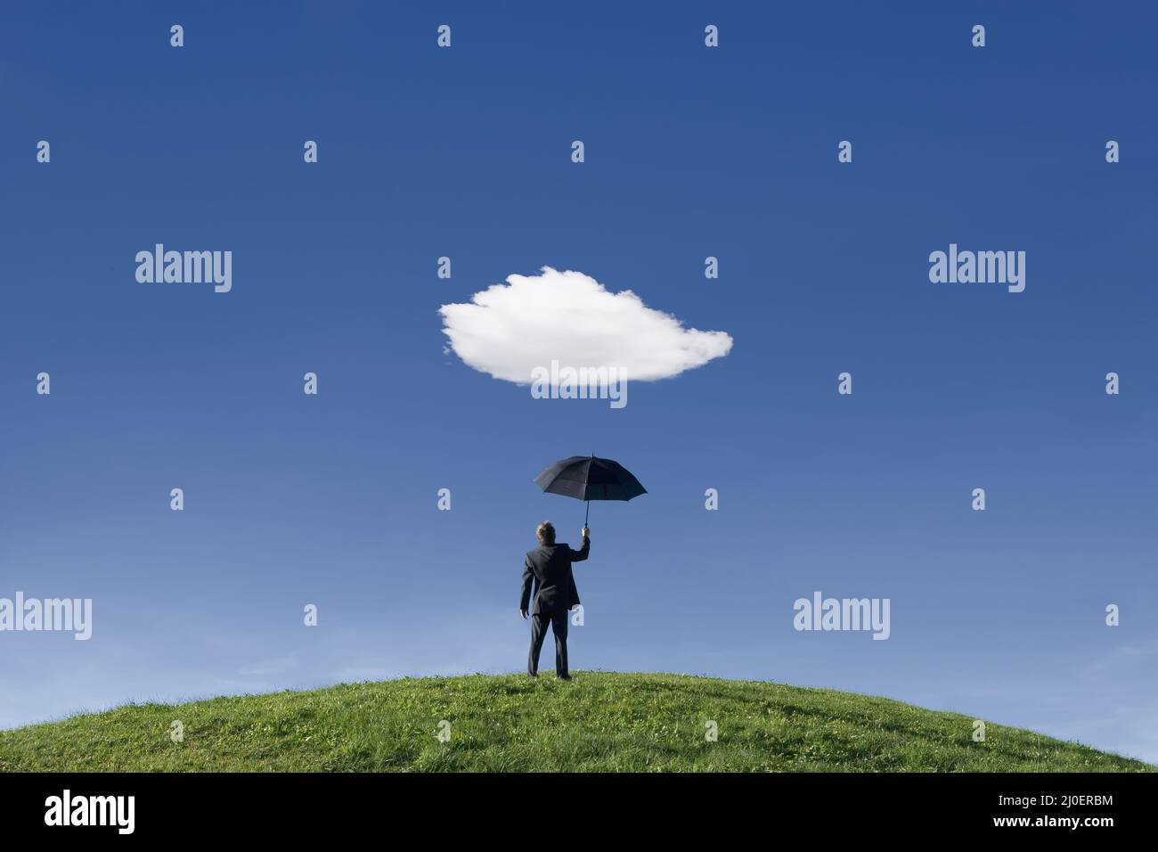 Geschäftsmann auf einem Hügel mit Regenschirm unter einer einzigen Wolke Themen des Antizipationsschutzes o Stockfoto