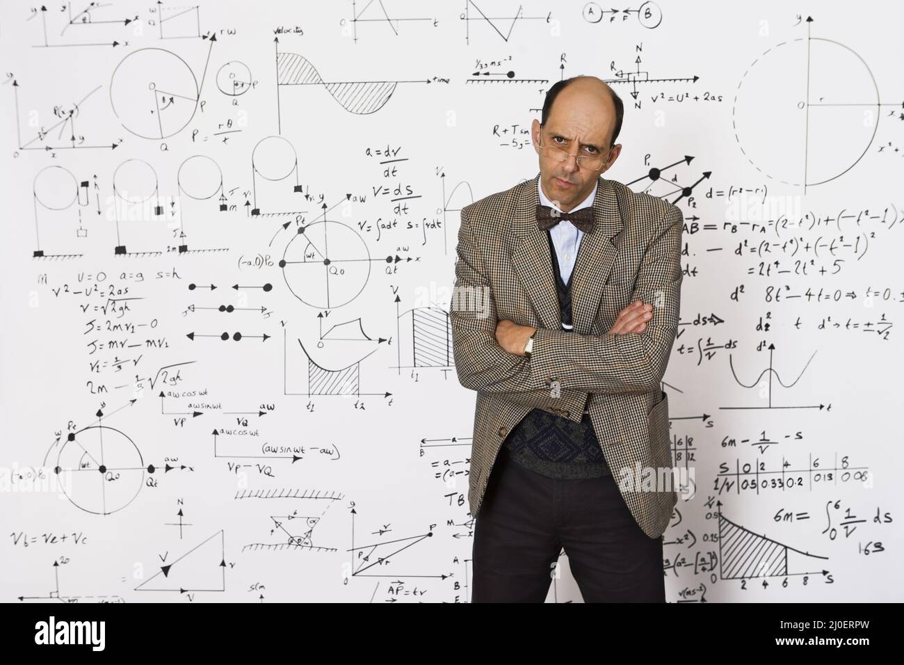 Kaukasischer Mathematiker mittleren Alters, der vor mathematischen Gleichungen auf einer weißen Wand steht Stockfoto