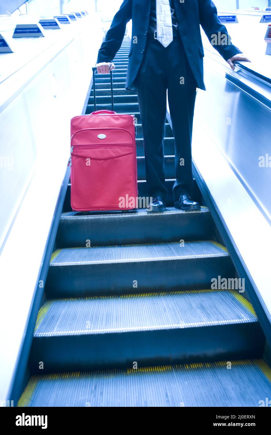 Geschäftsmann, der eine Rolltreppe hinunterfährt Stockfoto