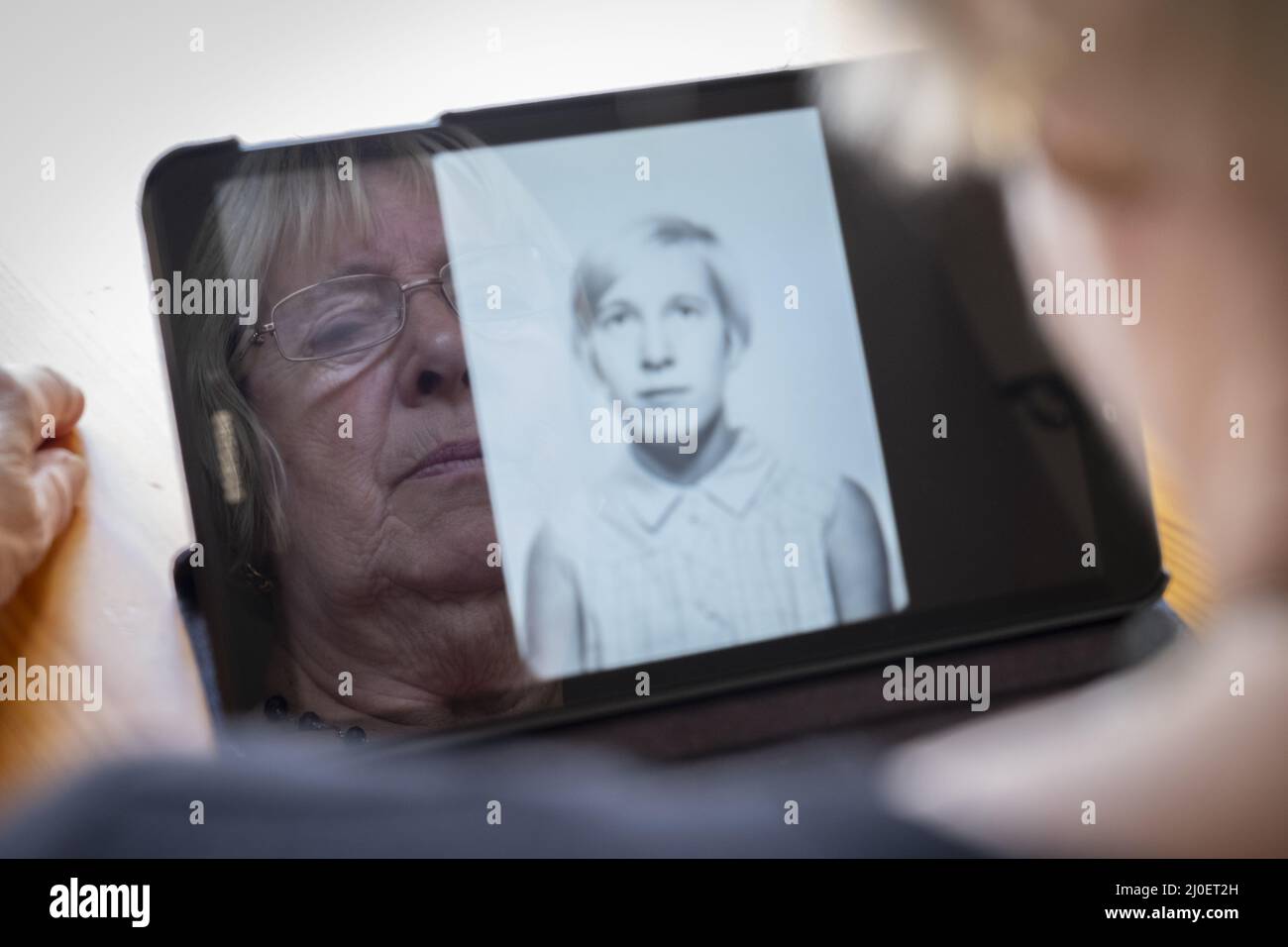 Senior kaukasische Frau an alte Fotos von sich selbst, als eine junge Frau auf einem Tablet-PC Stockfoto
