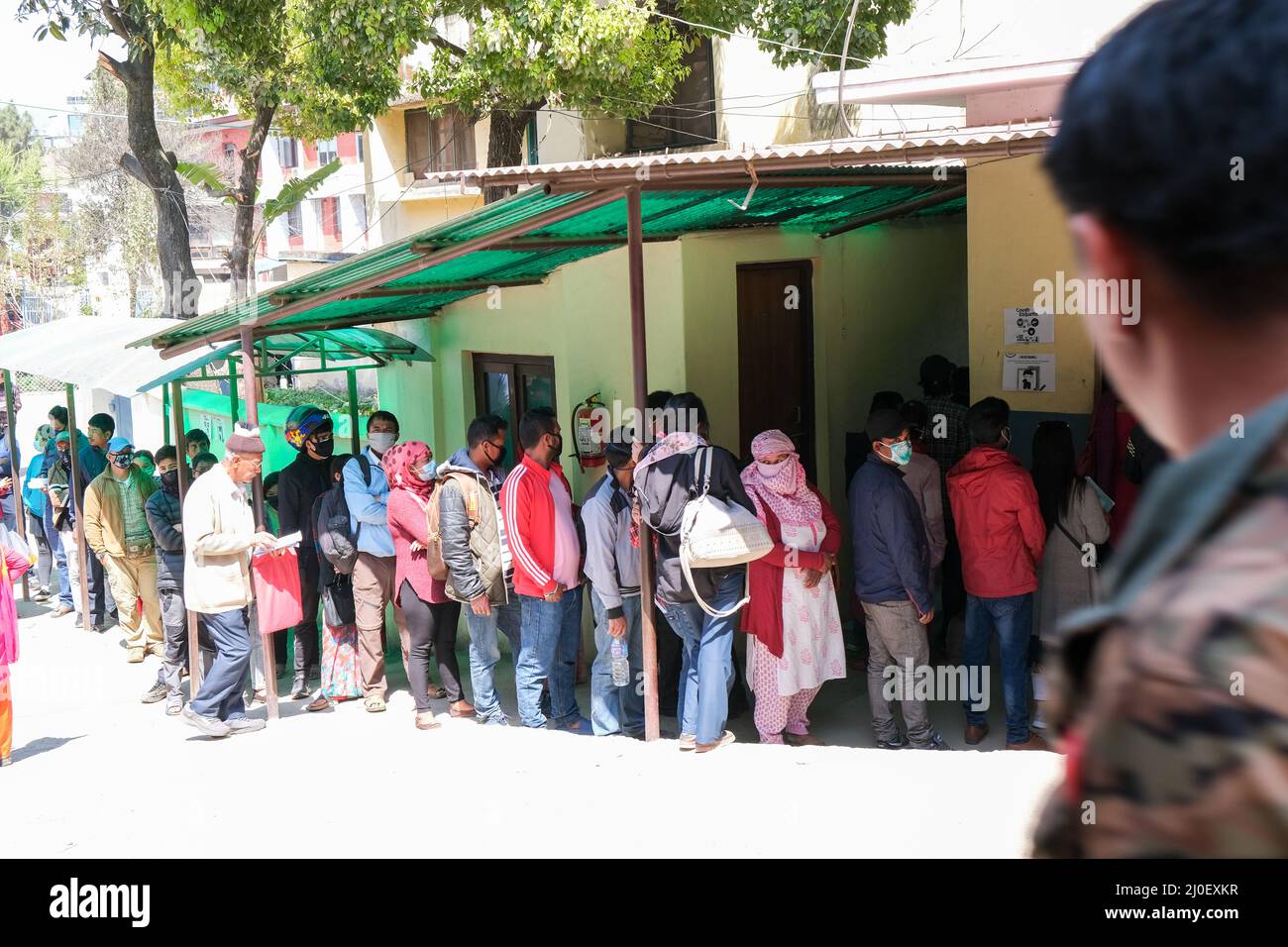 Menschen, die Schutzmasken vor einem Krankenhaus tragen und auf eine Untersuchung warten. Stockfoto