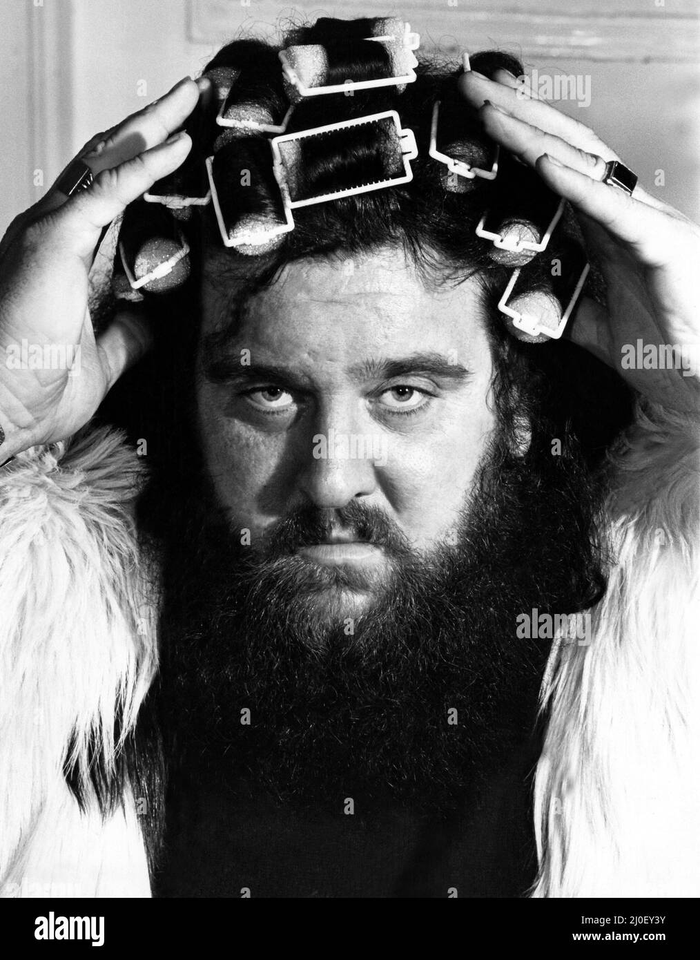 Ein Bild aus einer Serie humorvoller Neuheitenbilder, aufgenommen vom Sunday People-Fotografen Dennis Hutchinson. - Der Wrestler Giant Haystacks mit Rollen im Haar um: 1980 Stockfoto