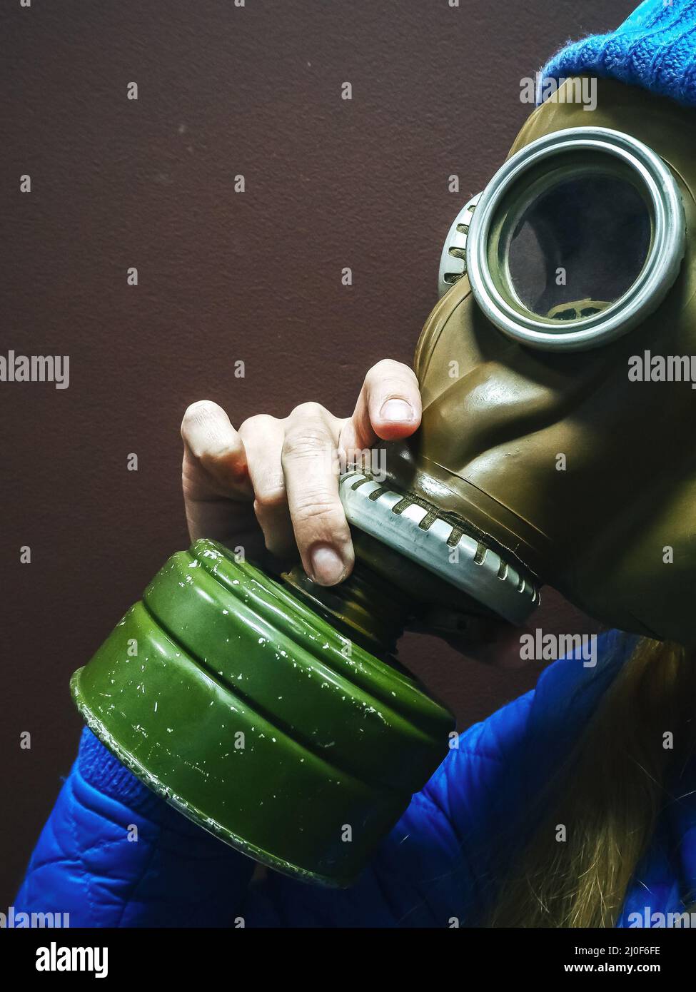 Nahaufnahme eines Mädchens, das eine alte sowjetische Gummifeuergasmaske anprobiert Stockfoto