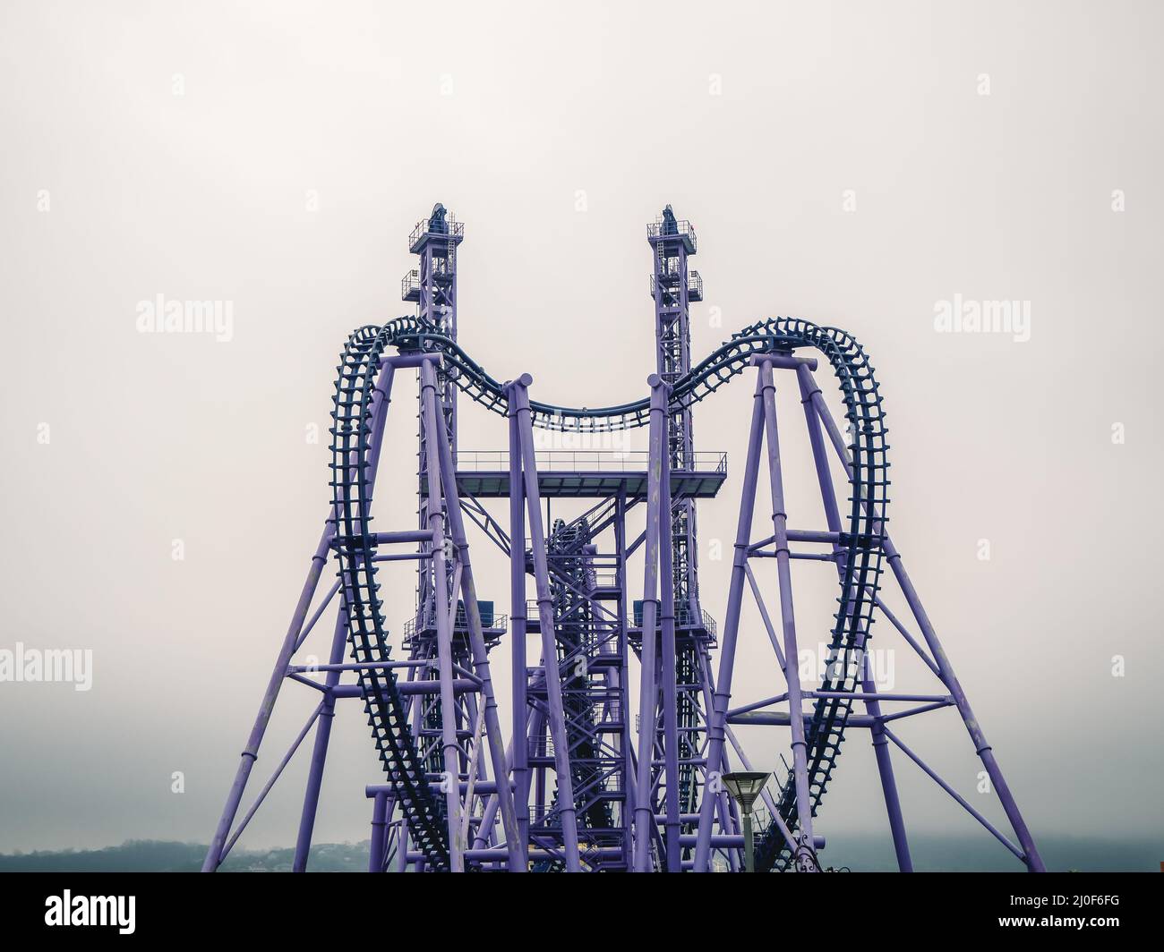 Flieder Achterbahn mit zwei hohen Türmen auf einem nebligen Himmel Hintergrund Stockfoto