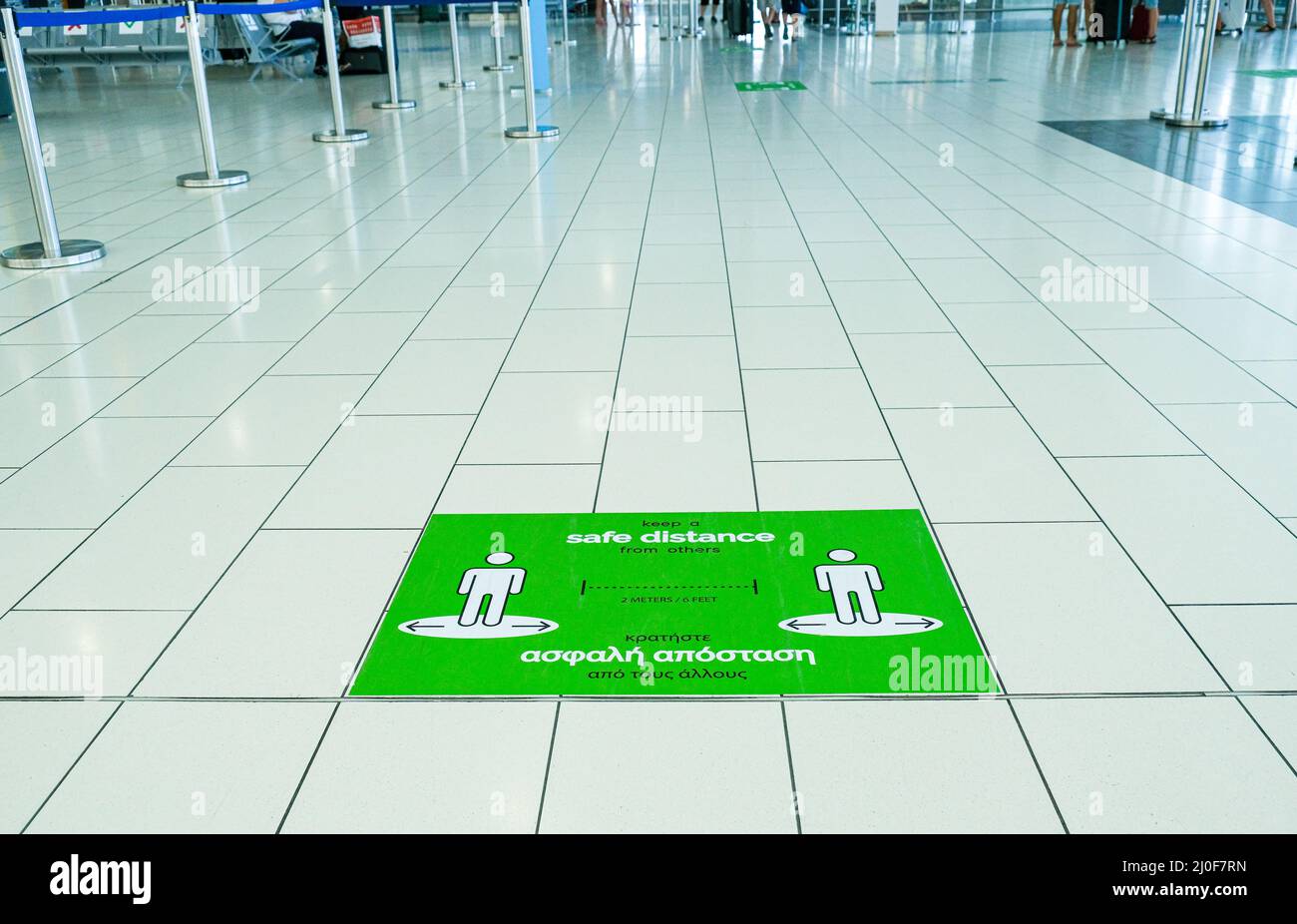 Warnschild auf dem Boden eines Flughafenterminals, um Abstand zum Schutz vor Corona zu sichern Stockfoto