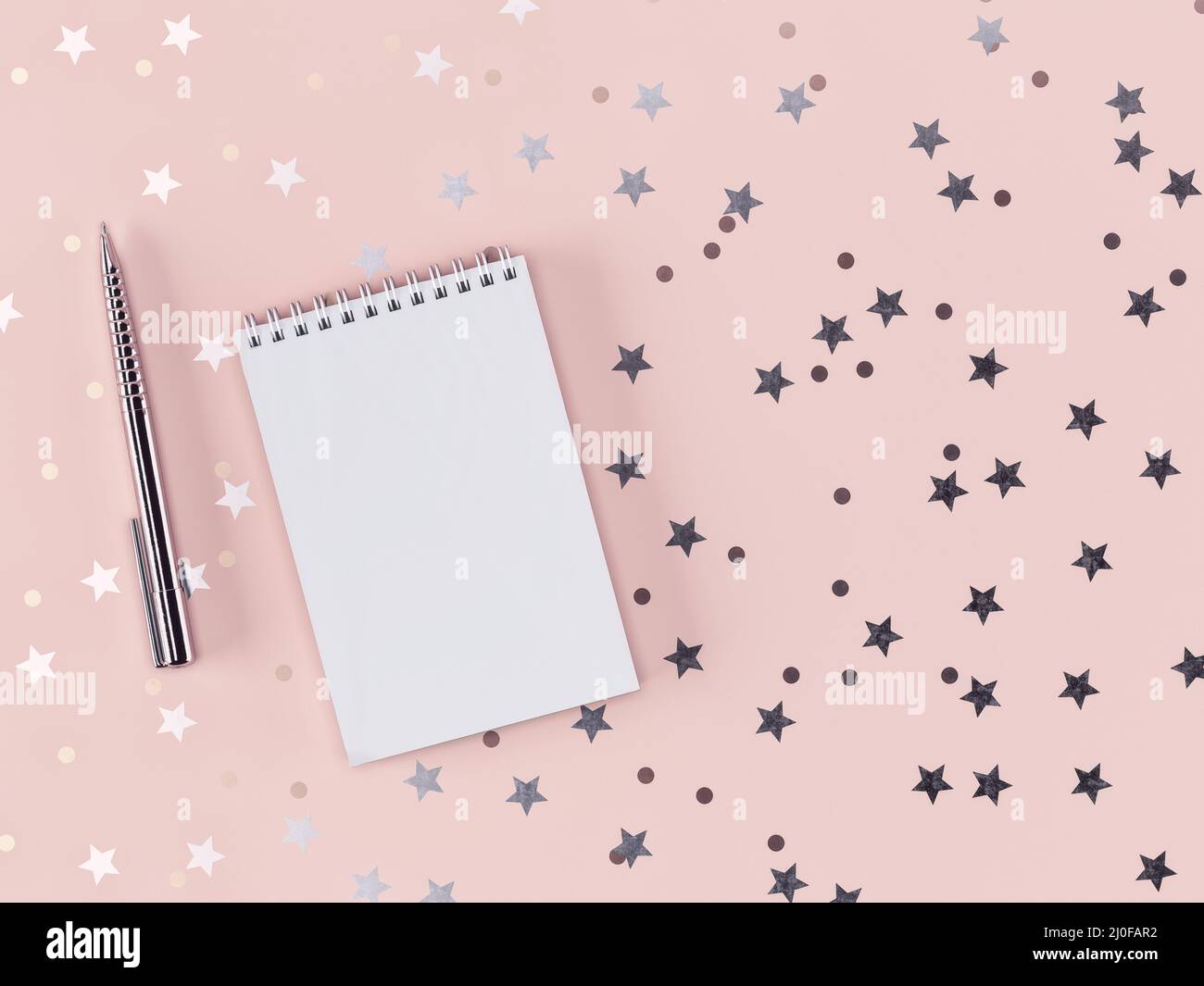 Stift und Notizbuch mit verstreuten Sternen und Kreisen auf einem zarten rosa Hintergrund. 3D-Rendering Stockfoto