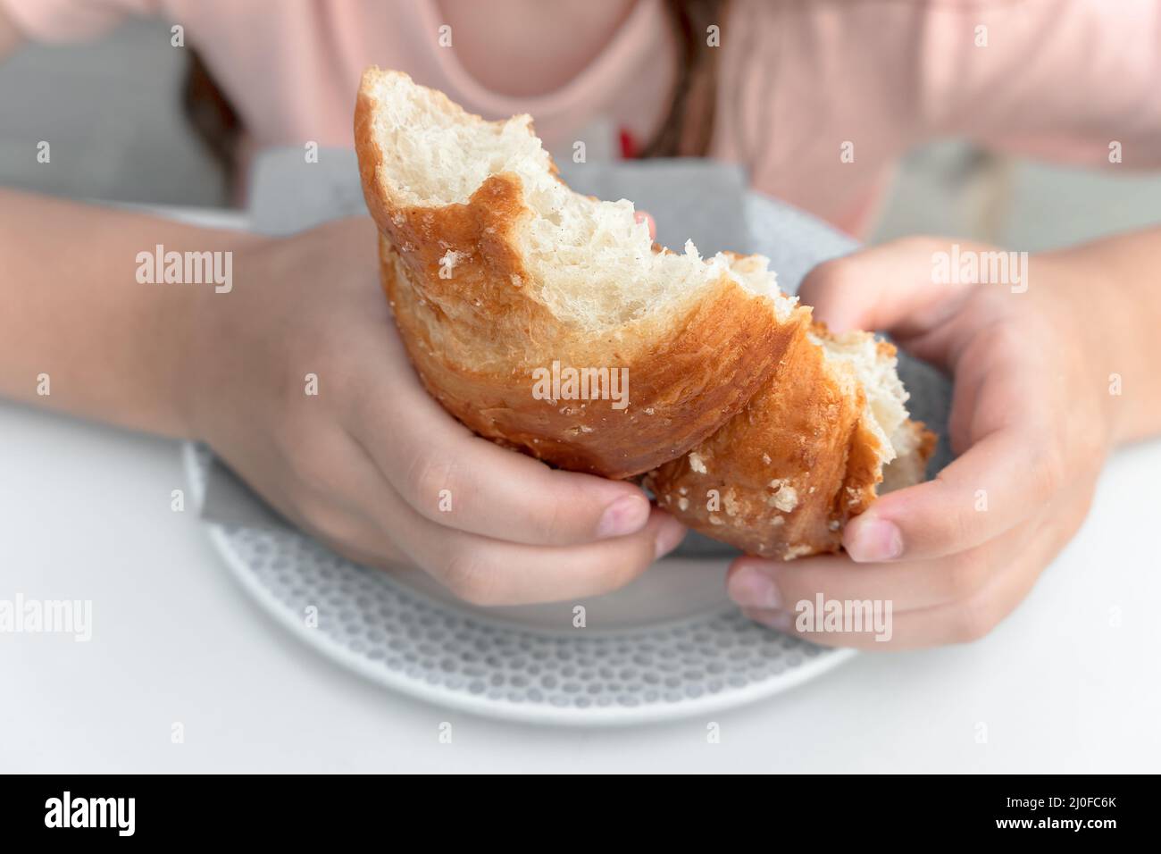 Junges Mädchen essen Croissant Stockfoto