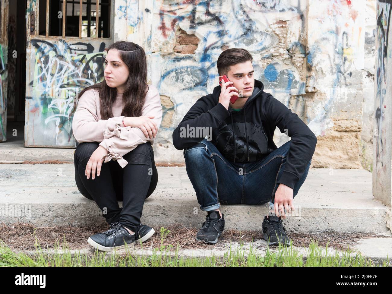 Junge Teenager sprechen auf dem Mobiltelefon und ignorieren das Mädchen. Konzept der Mobilen sucht Stockfoto